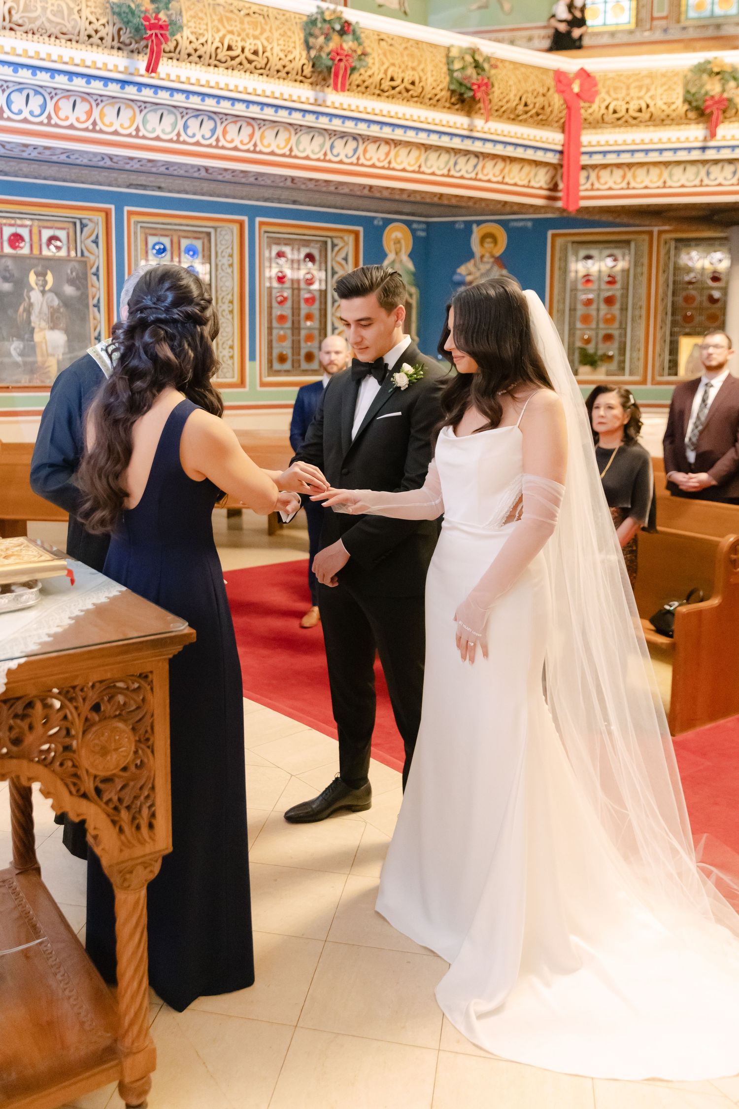 Wedding ceremony in a Byzantine church with ornate decorations and a red carpet aisle.