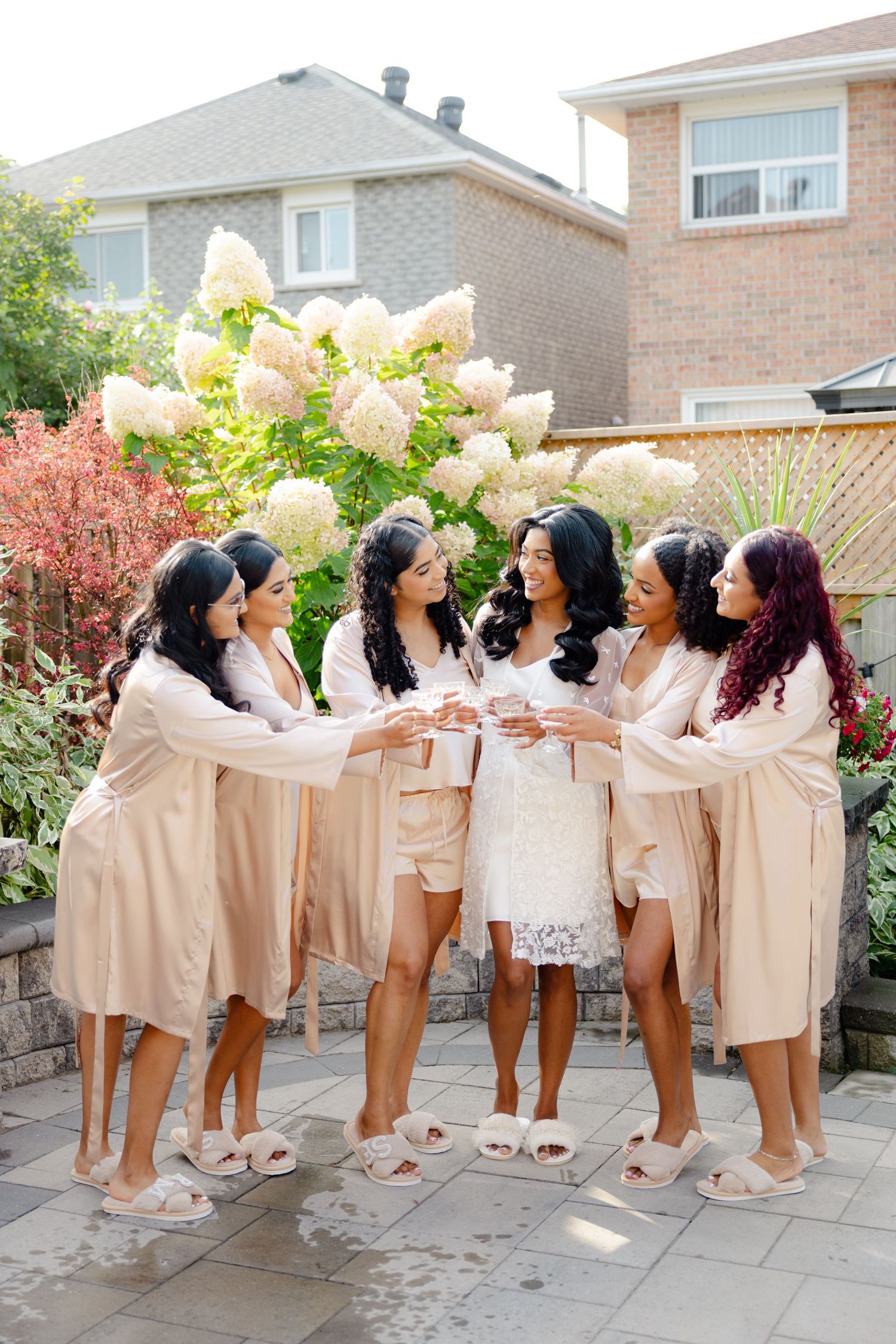 Bridesmaids gather in a circle wearing matching silk robes during pre-wedding celebrations.