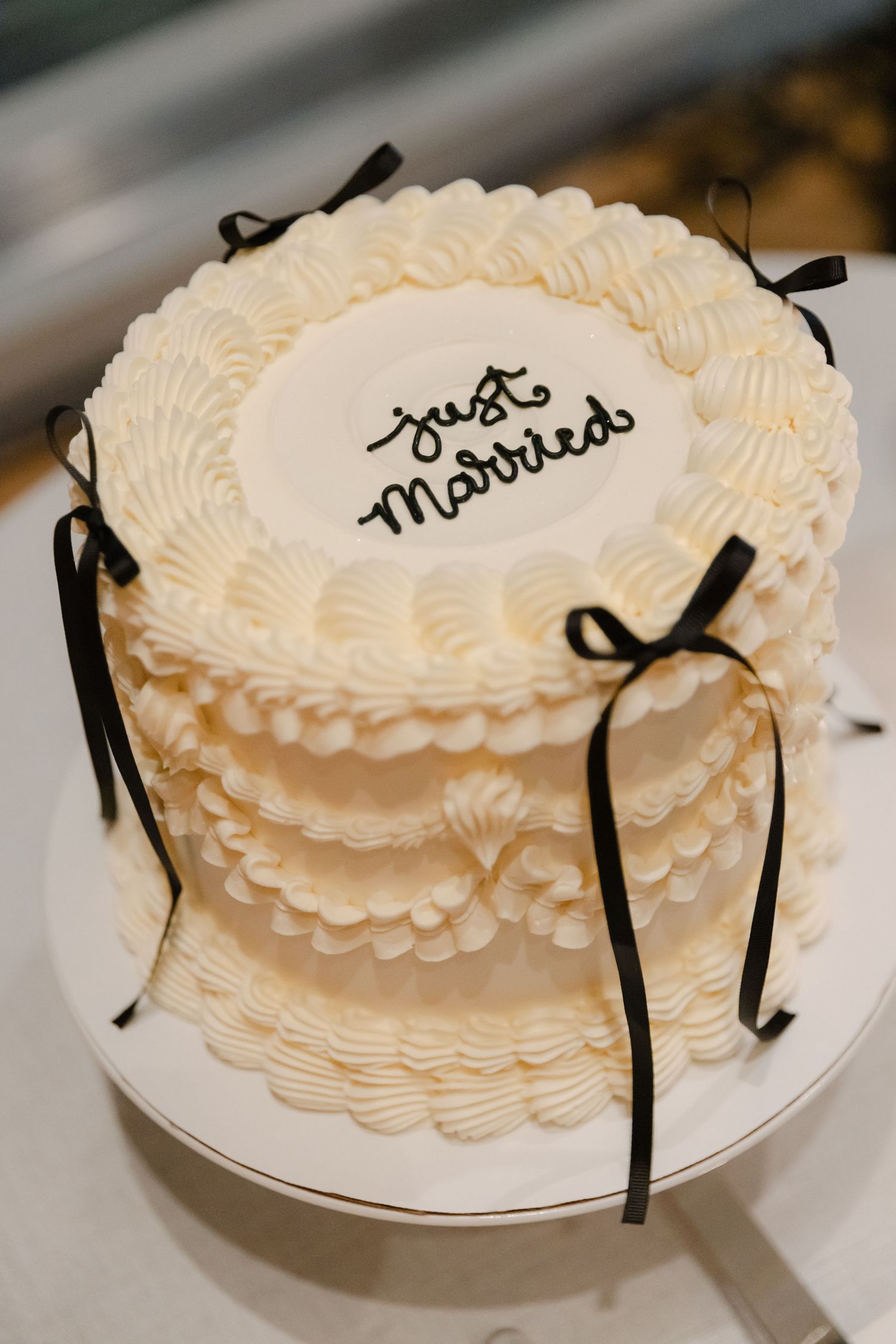 Just Married wedding cake with cream-colored buttercream piping and black ribbon details.