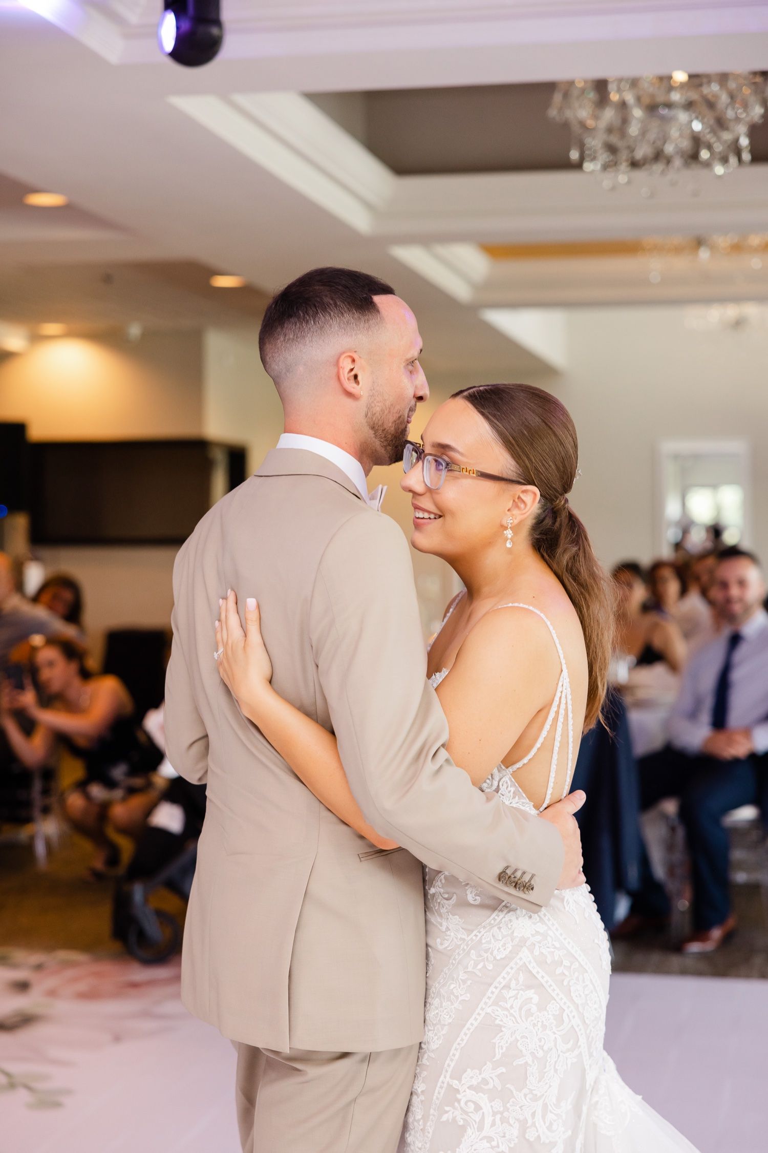 Tender moment during first dance at wedding reception with soft natural lighting.