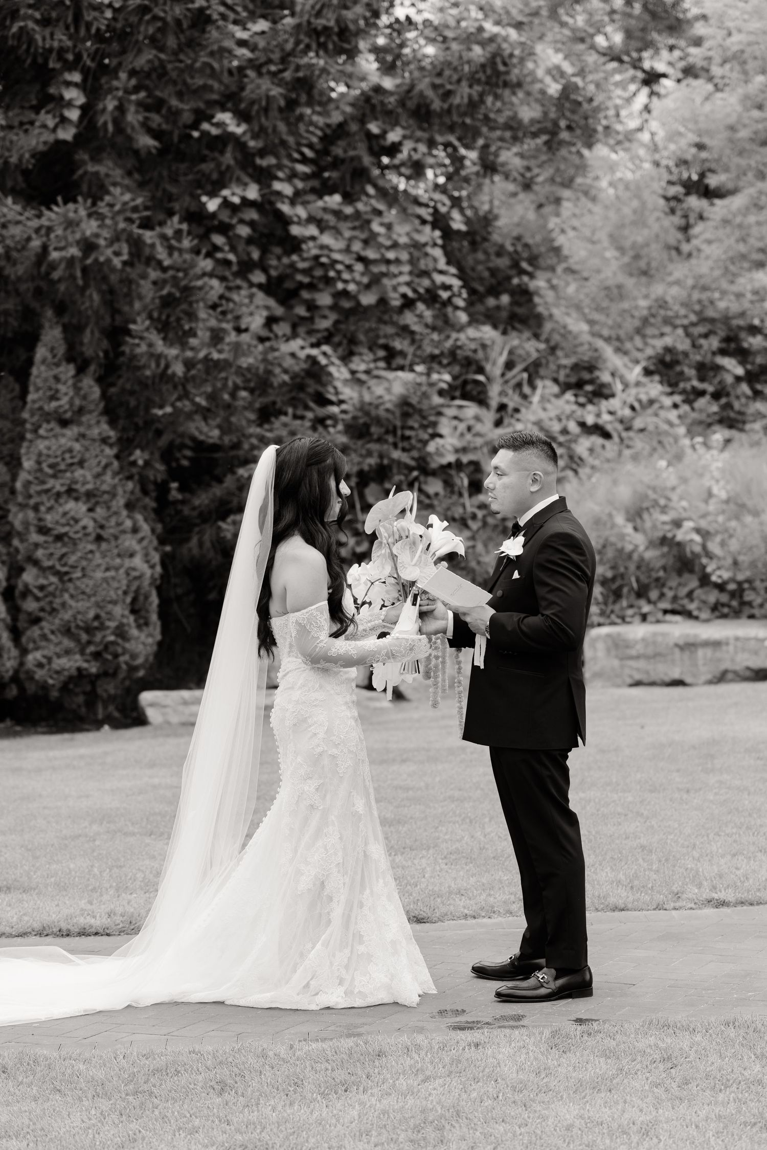 A romantic first look between newlyweds in a garden setting captured in a black and white photo series.