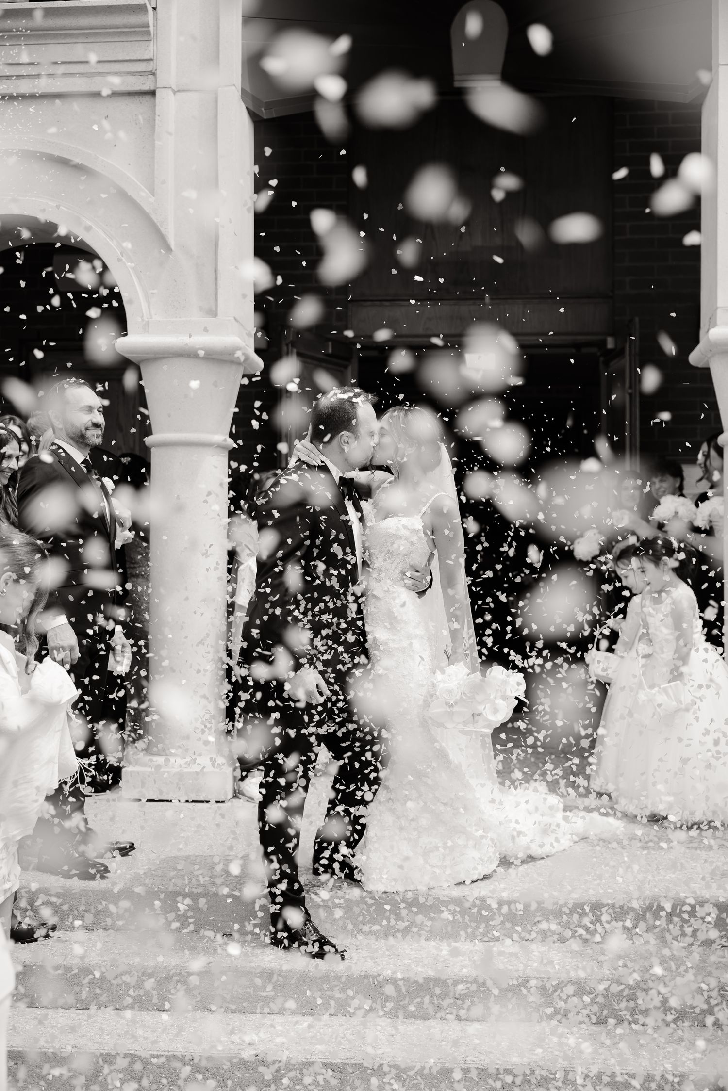Silhouettes captured in black and white against splashing water fountain on a sunny day.