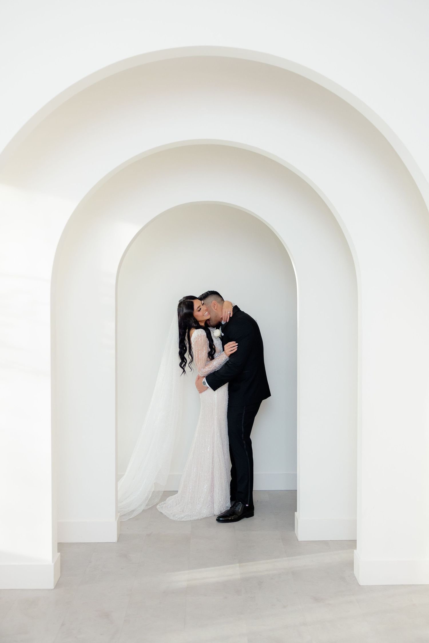 Artistic wedding photo showing couple's silhouette framed by concentric white arches.
