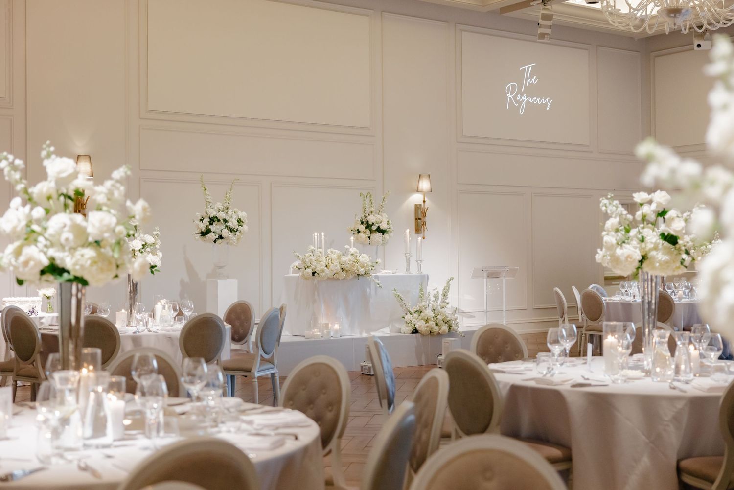 Dreamy wedding reception setup with soft lighting, white floral centerpieces, and elegant table settings.