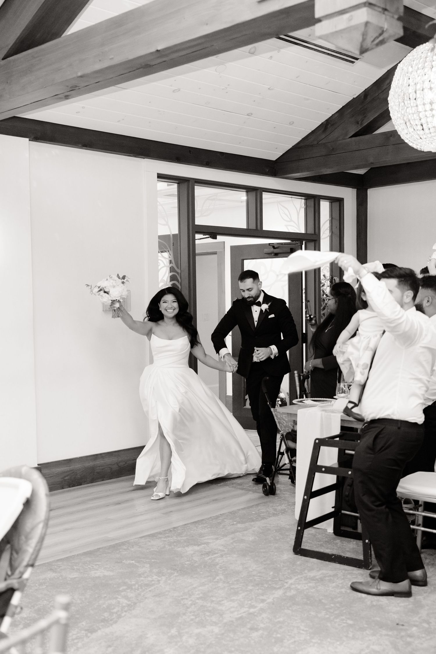Grand entrance into wedding reception venue with decorative lighting and wooden beam architecture.