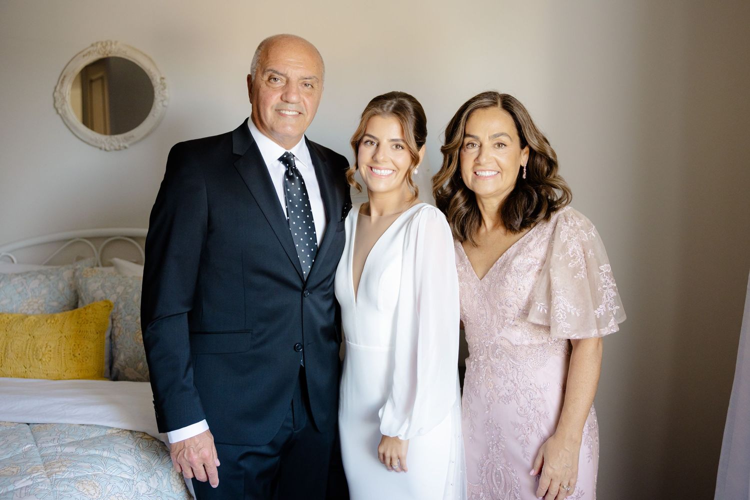 Group portrait in neutral tones with bride in white gown and family members in formal wear.
