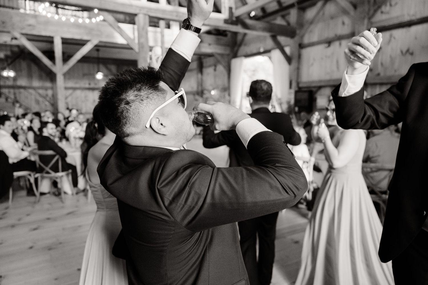 Black and white photo of energetic dancing during a barn wedding reception.