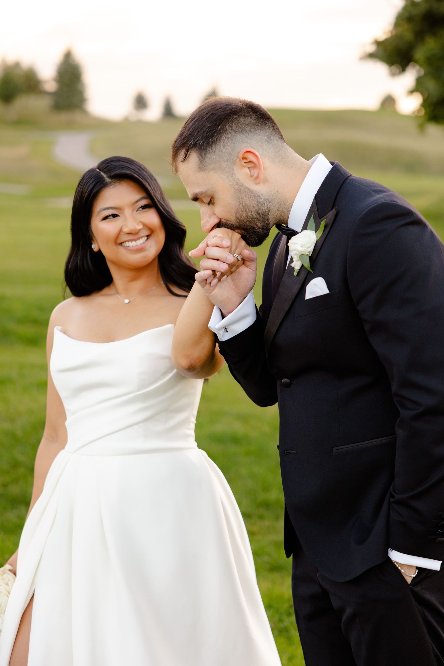 An intimate wedding portrait showing a sweet moment between the couple on a green lawn.