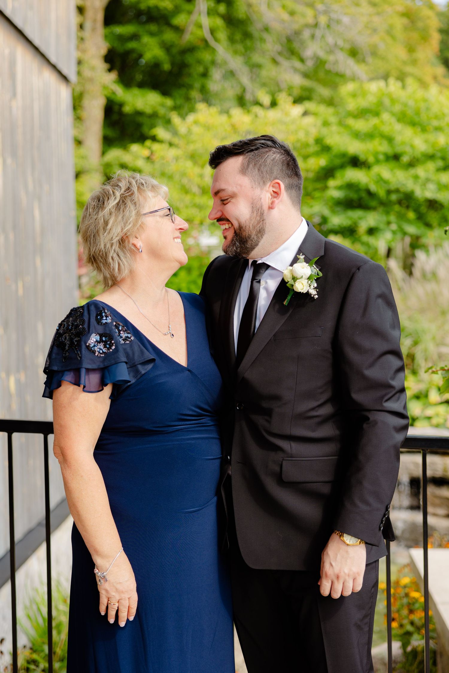 Candid moment captured between two people in formal attire on rustic wooden deck.