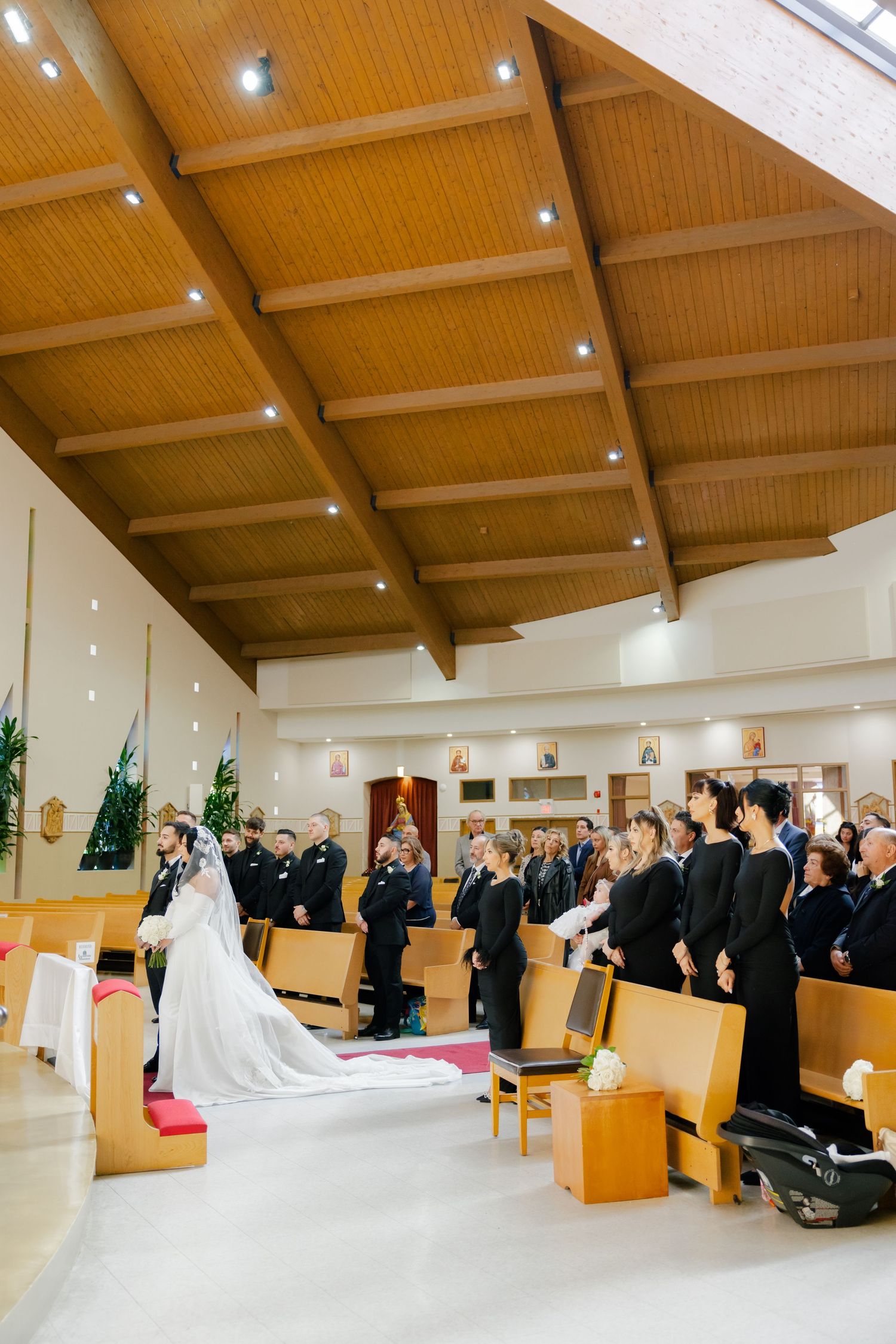 Wedding ceremony in a church with wooden beam ceiling and guests seated in pews.