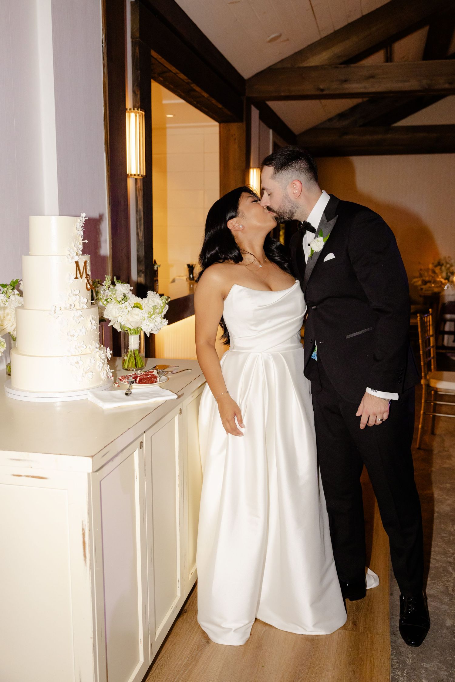 Romantic moment between newlyweds next to their elegant white wedding cake.