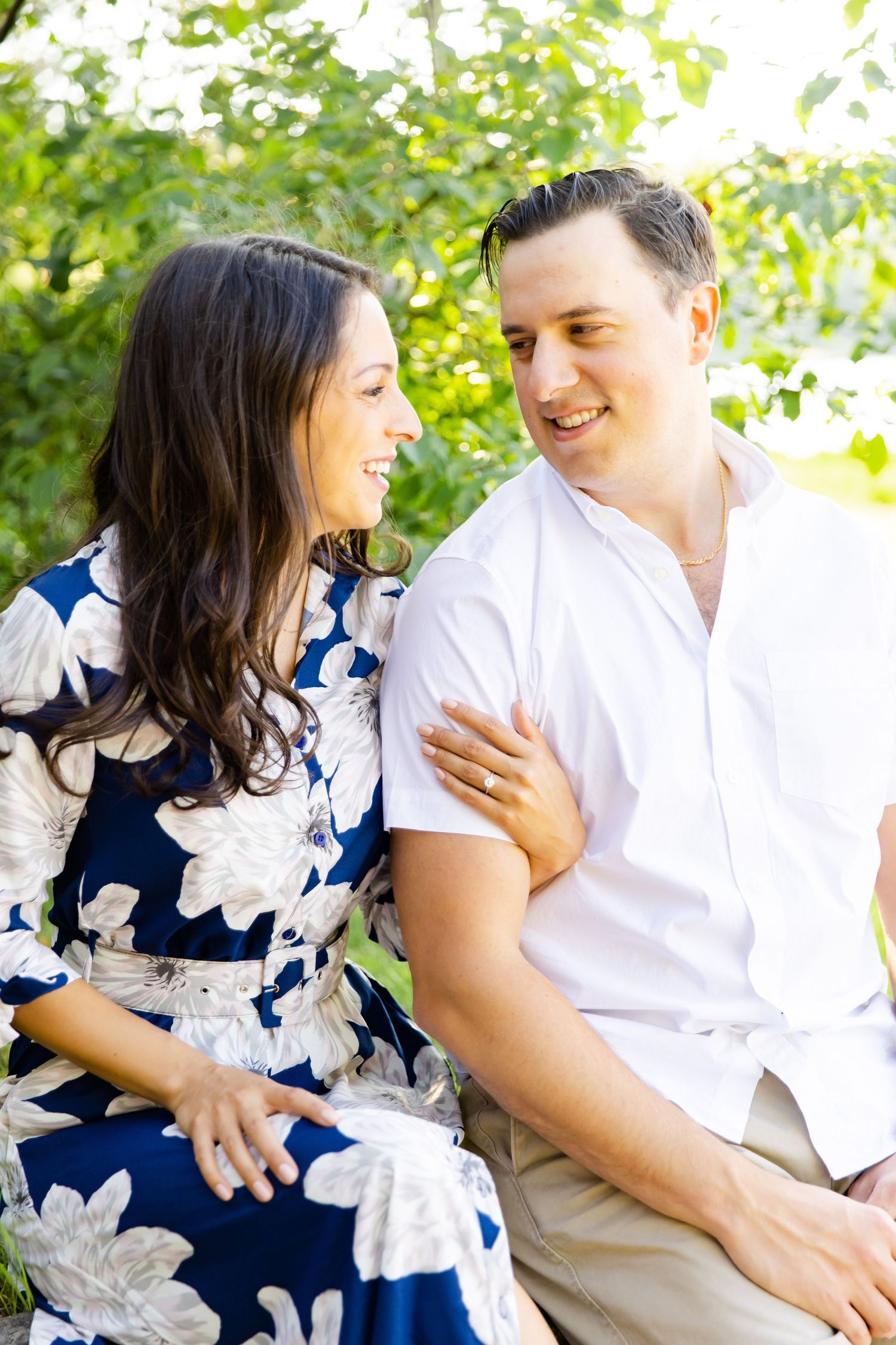 A couple sharing a tender moment outdoors while wearing coordinated white and floral outfits.