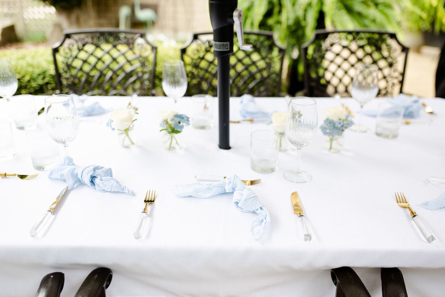 Elegant outdoor table setting with white linens and patio chairs arranged for a special event.