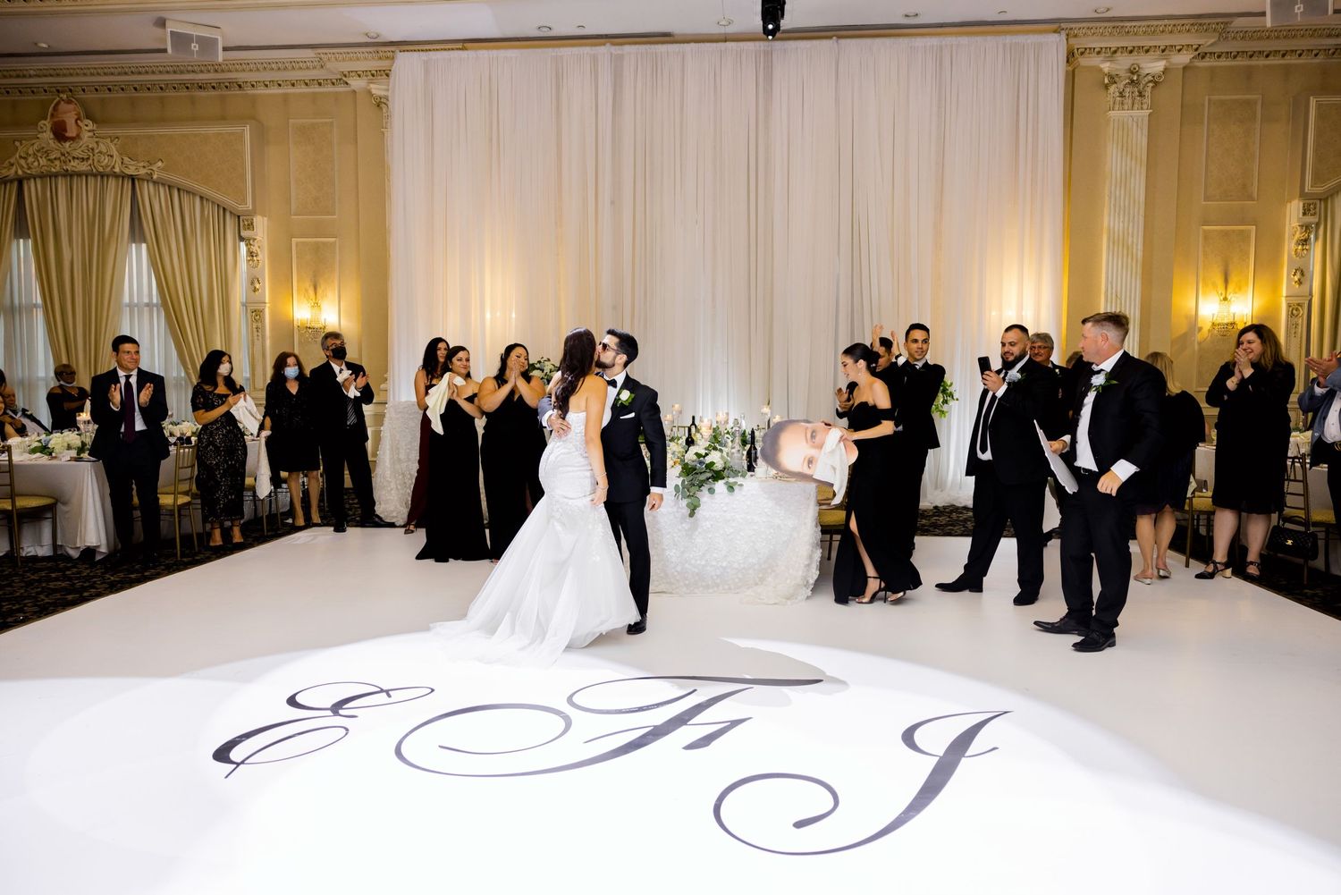 Wedding reception with monogrammed dance floor and guests celebrating.