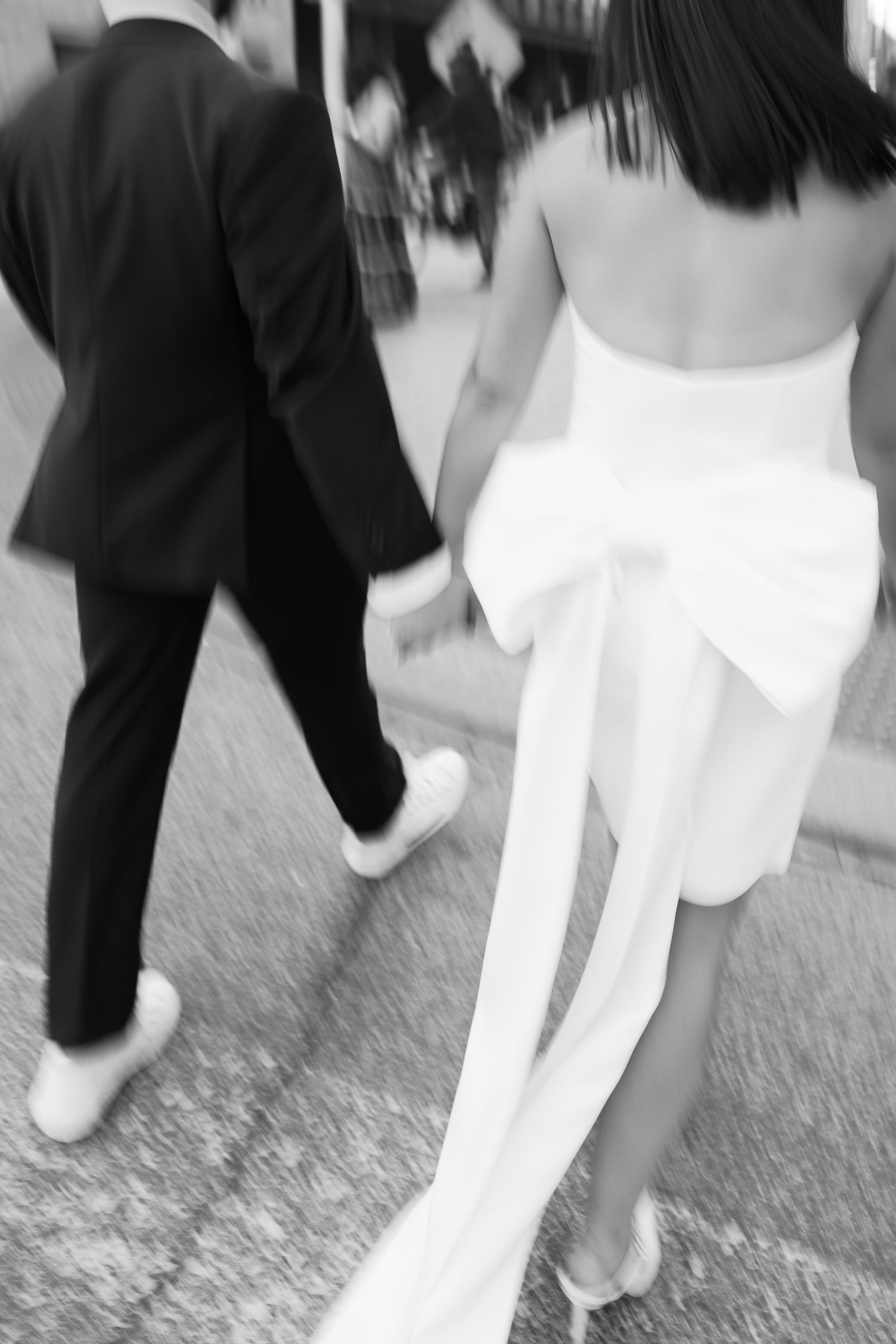 Motion blur capture of couple walking together showing formal dress and suit details.