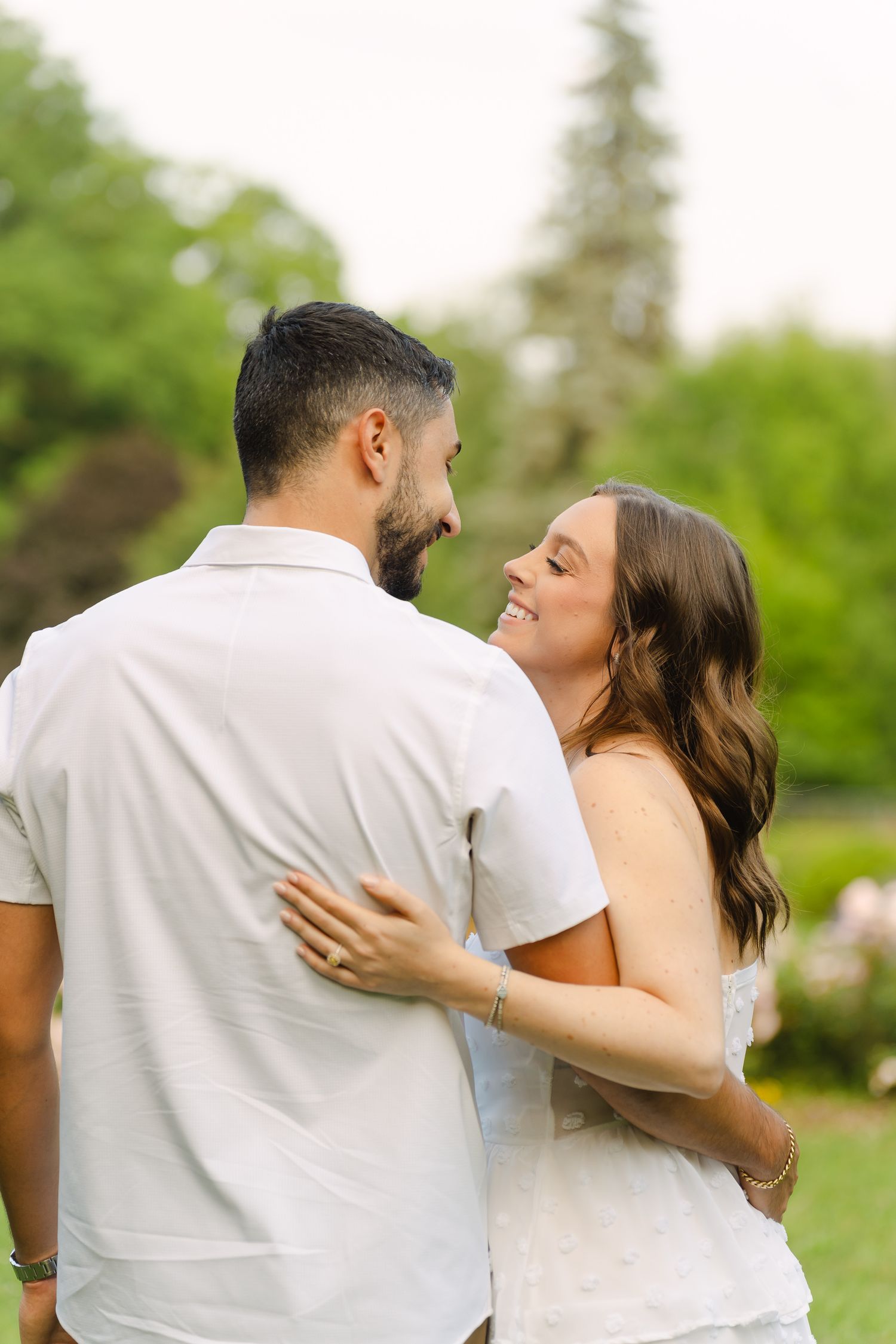 A joyful moment between a couple in a garden setting with lush greenery in the background.