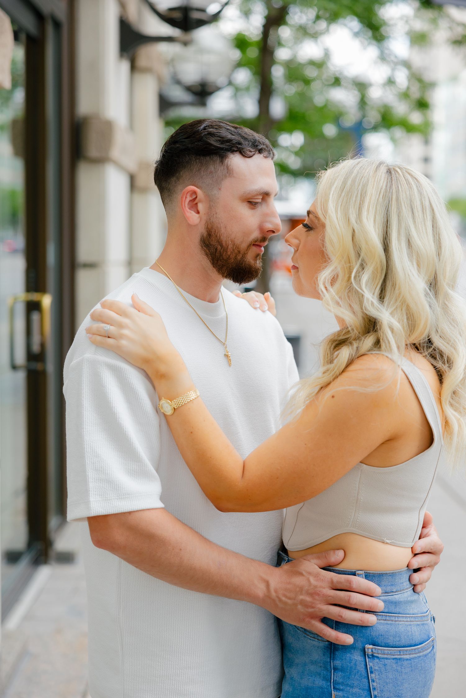 An affectionate couple in casual wear embracing on a city street.
