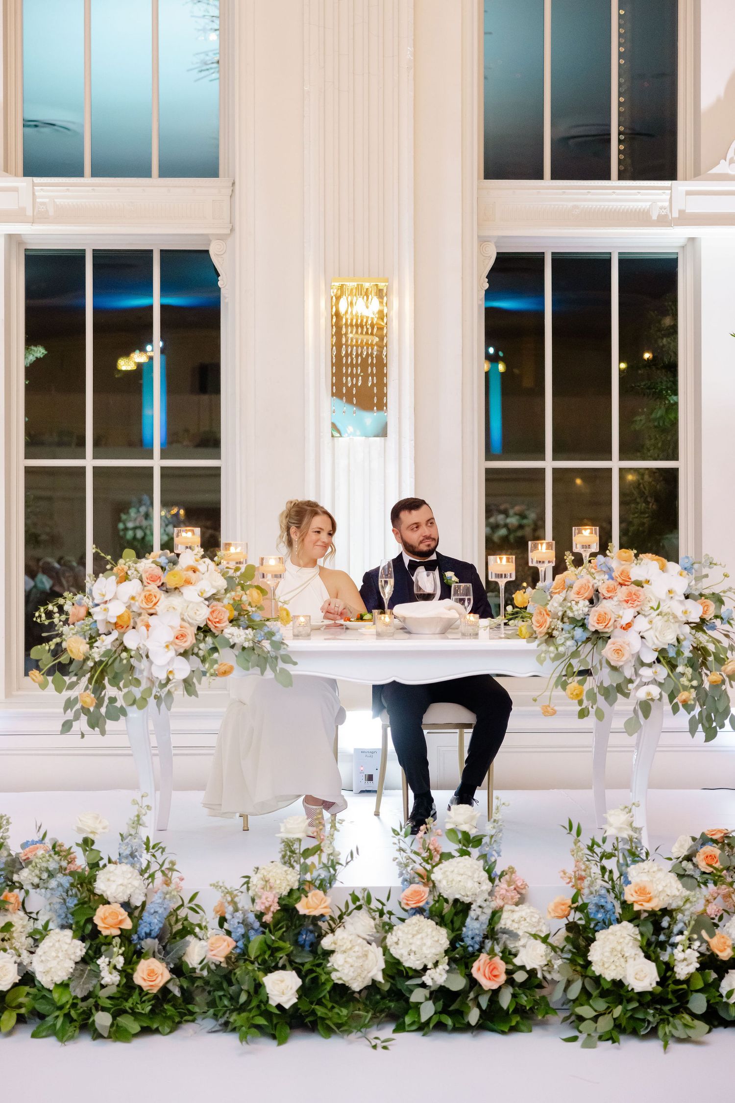 Wedding reception venue with lush peach and white floral arrangements along the stage.