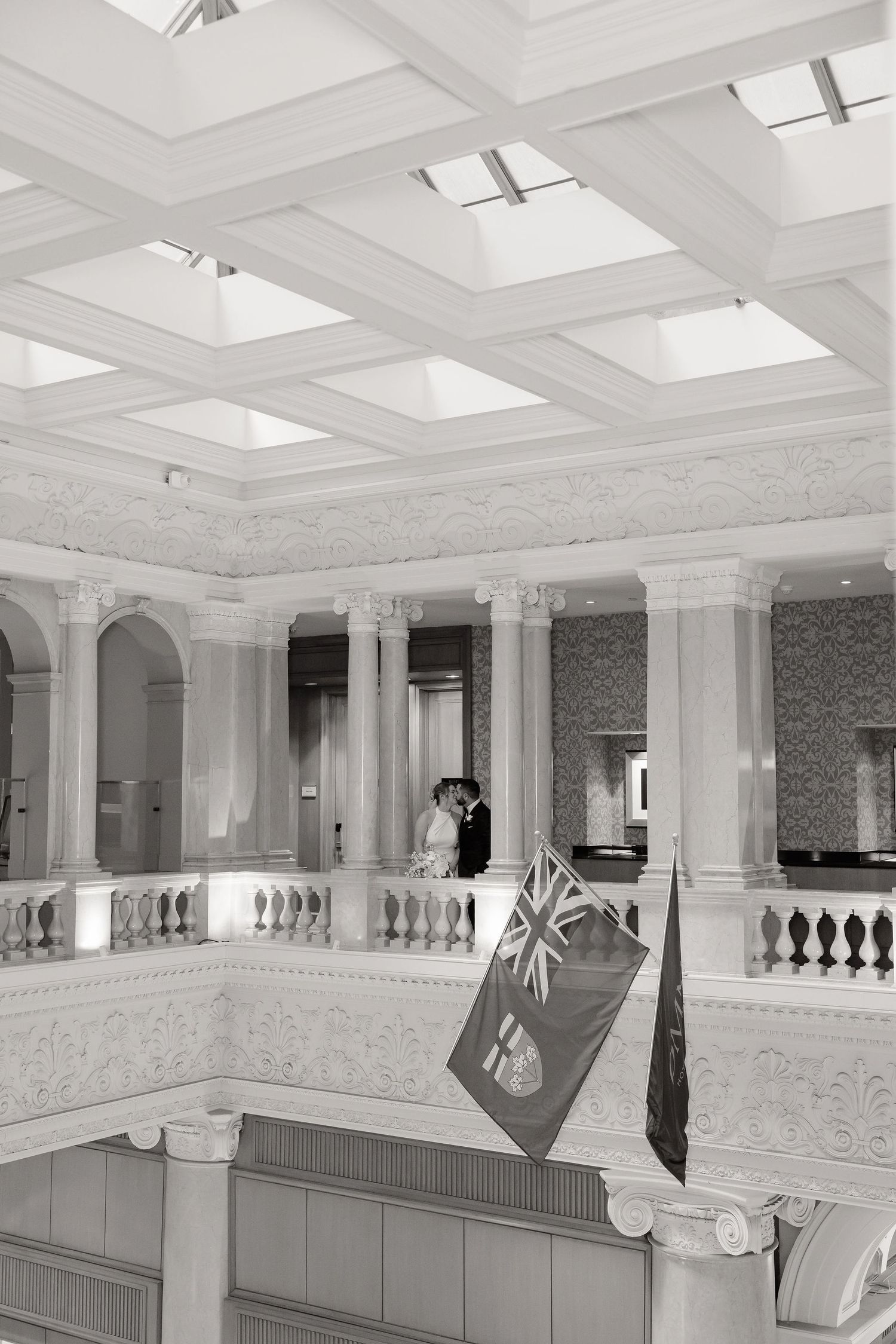 Elegant interior architecture of a historic building with ornate columns, skylights and a hanging flag.