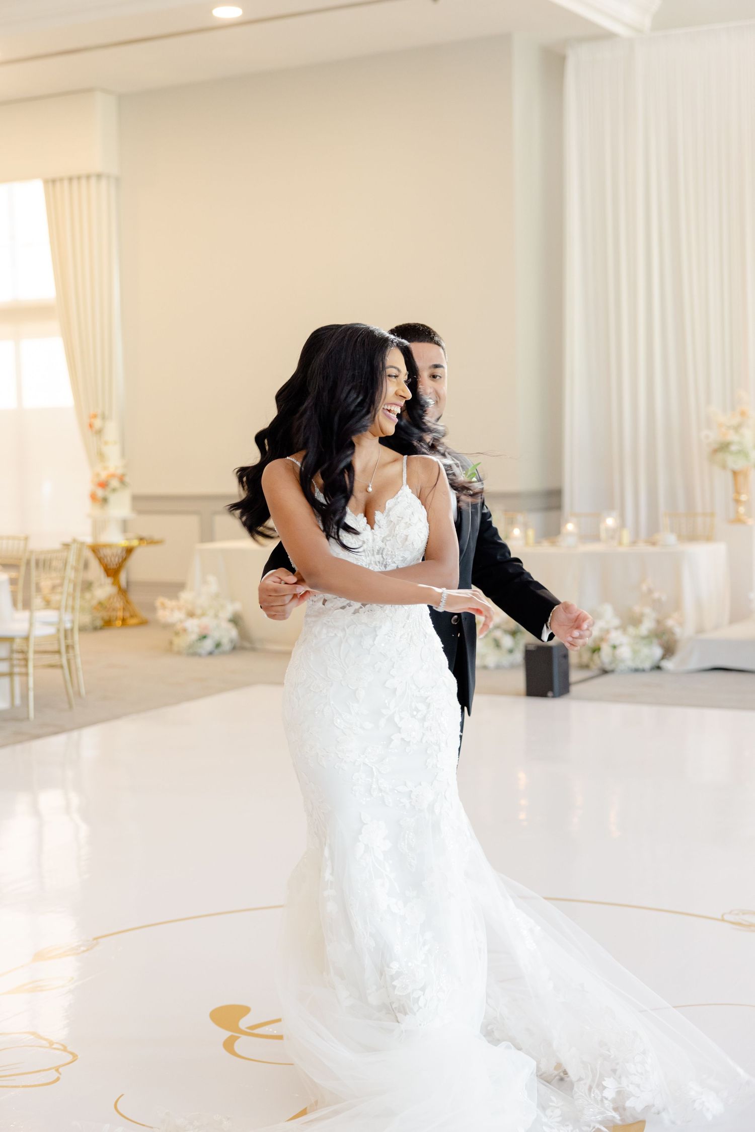 Wedding couple sharing an intimate dance moment in an elegant white ballroom.
