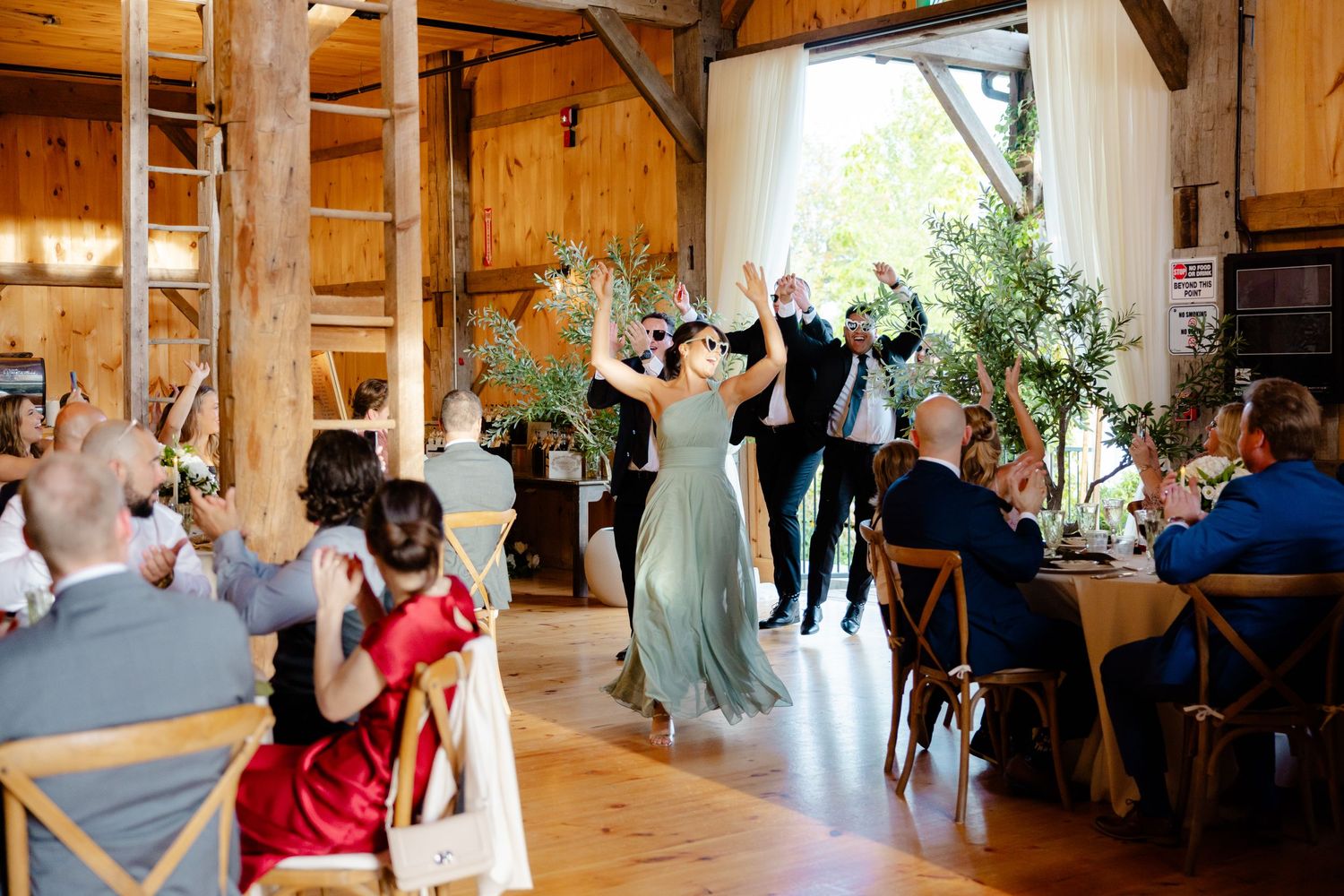 Wedding celebration in a rustic barn venue with guests dancing and cheering.
