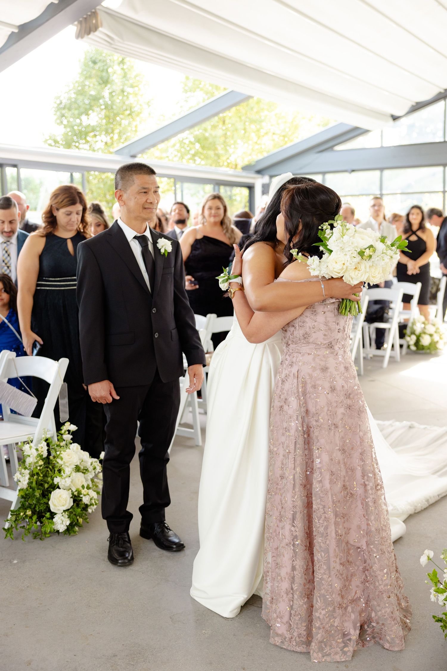 Wedding ceremony moment in a bright indoor space with white and floral decorations.