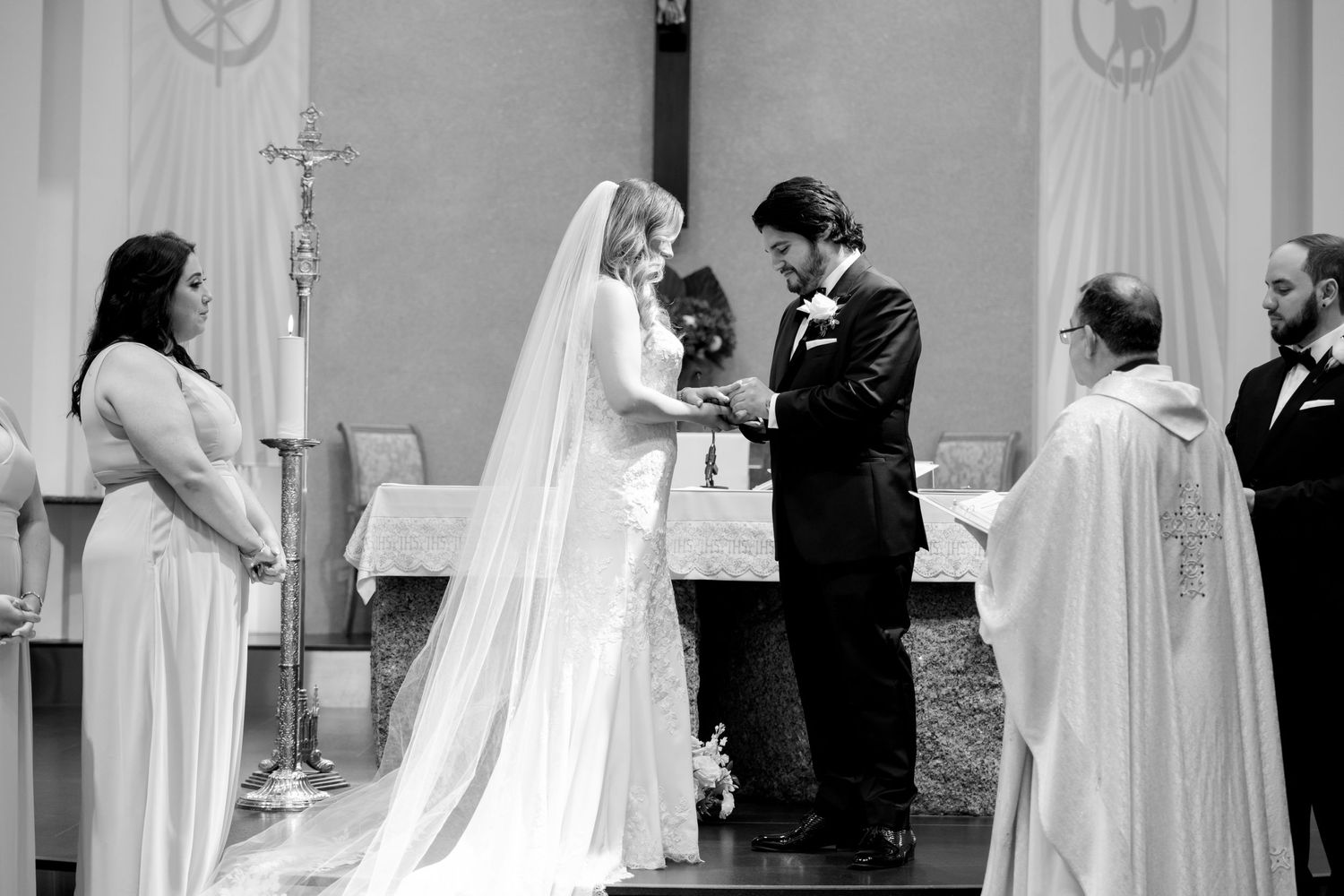 Black and white image of wedding ceremony with priest officiating at church altar.