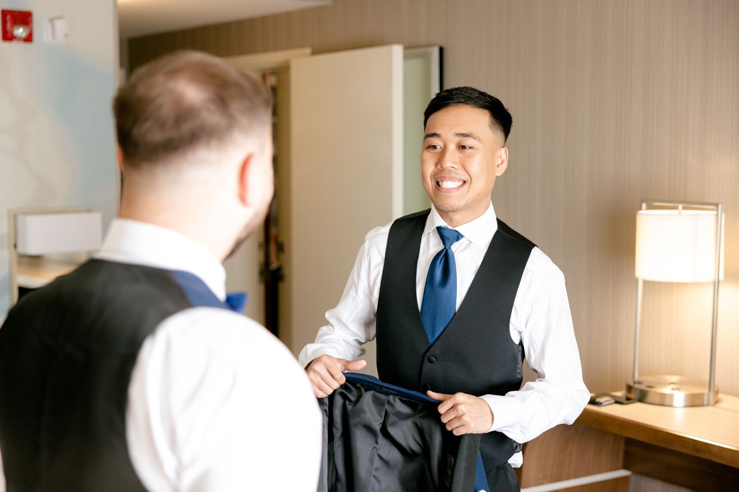 Two people in formal wear having a conversation in a hotel room.