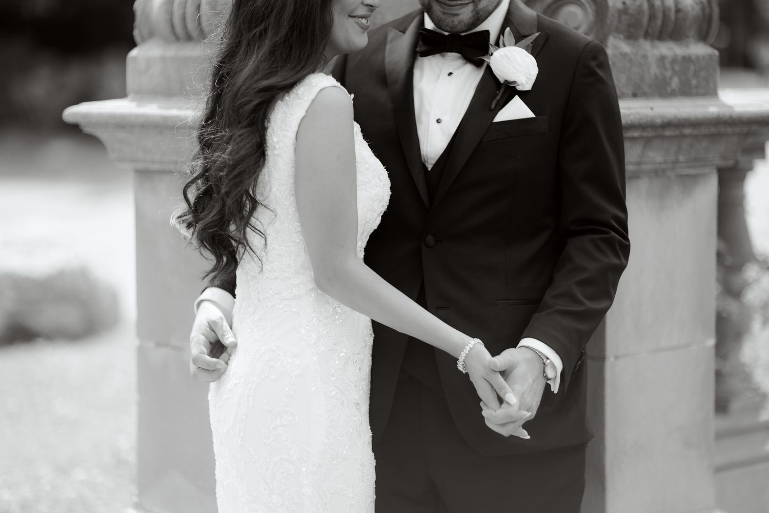 Black and white wedding photo showing a romantic moment between a couple in formal attire.