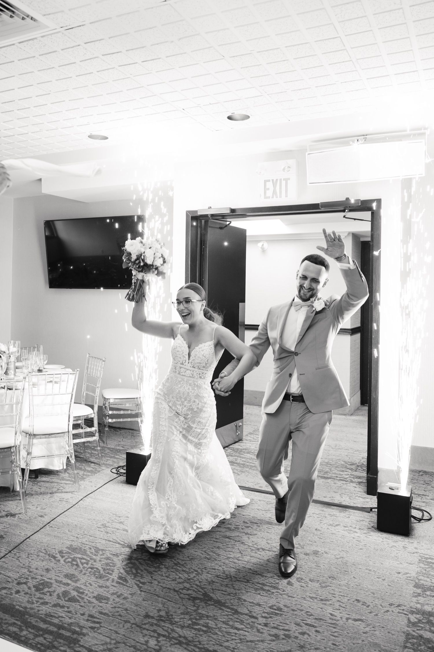 Black and white photo of a joyful wedding reception entrance with festive dancing.
