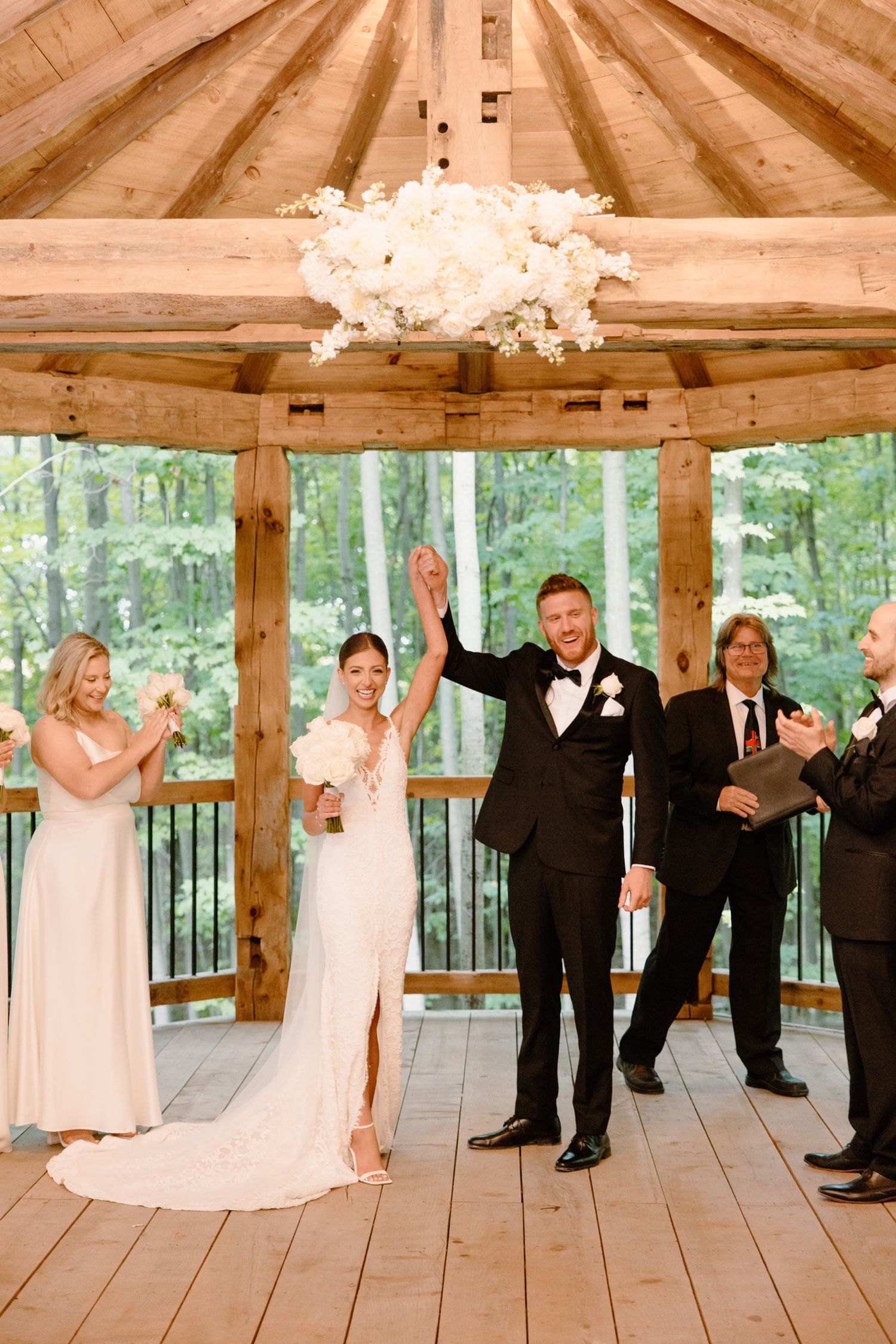 Joyful celebration moment under a wooden gazebo's vaulted ceiling with crystal chandelier.