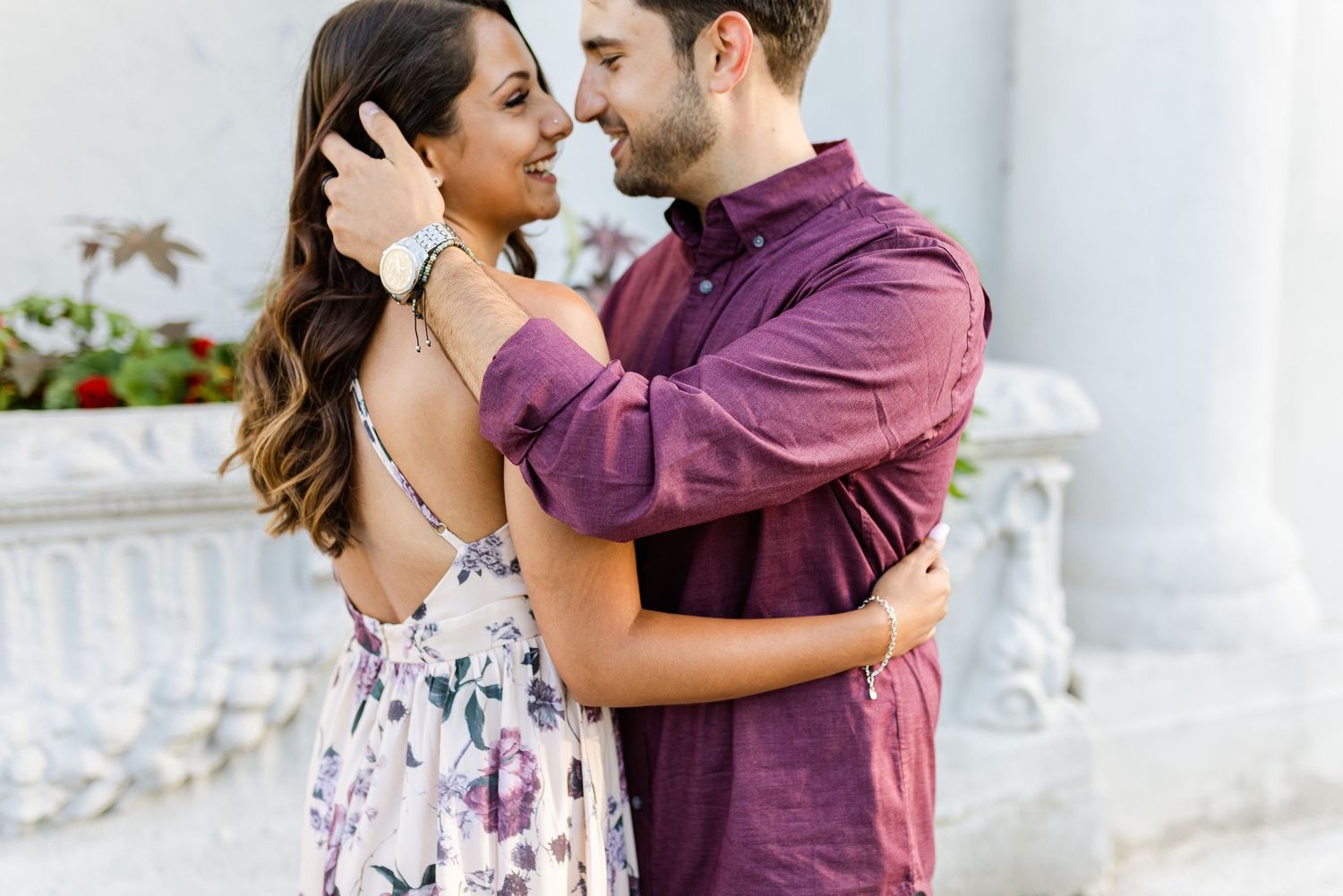 Couple sharing intimate embrace against white architectural backdrop.