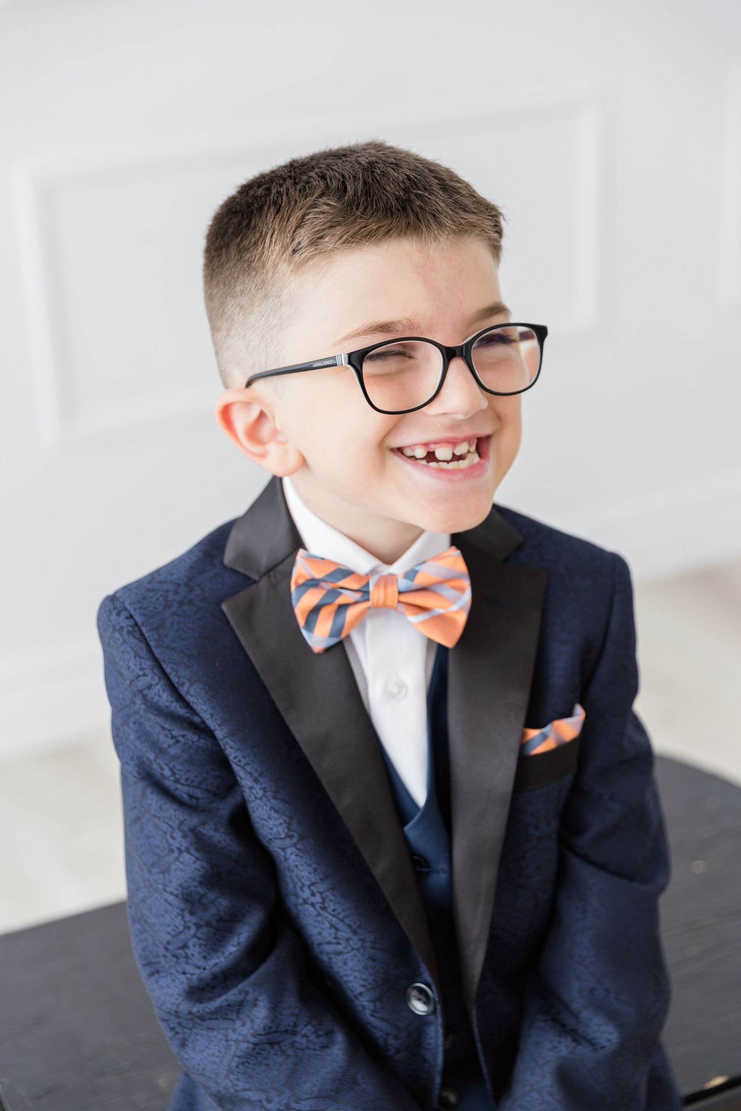 Portrait of youth in formal navy suit and striped bowtie smiling at camera.