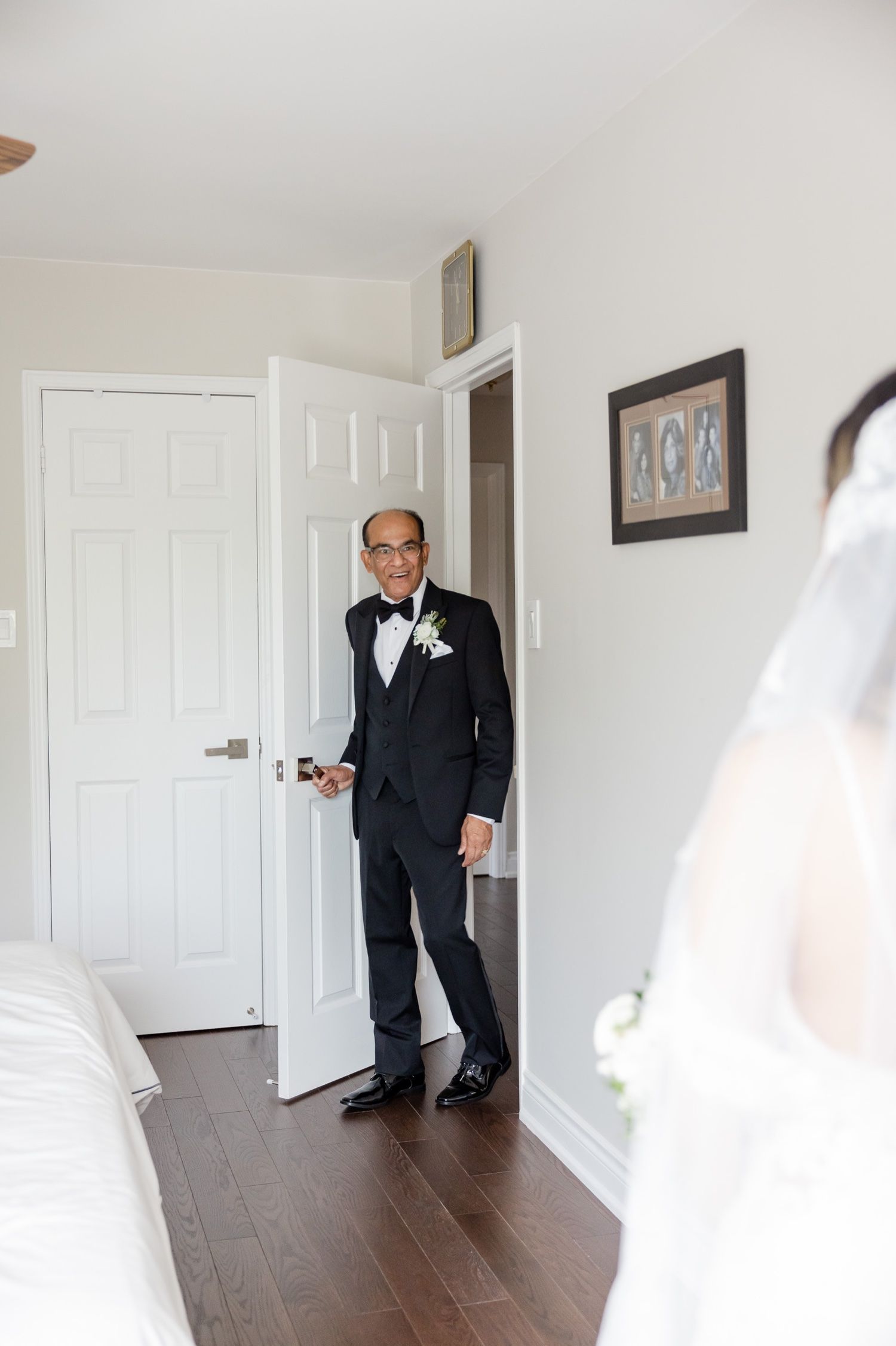 A formal first look moment between loved ones in a minimalist room with white doors.