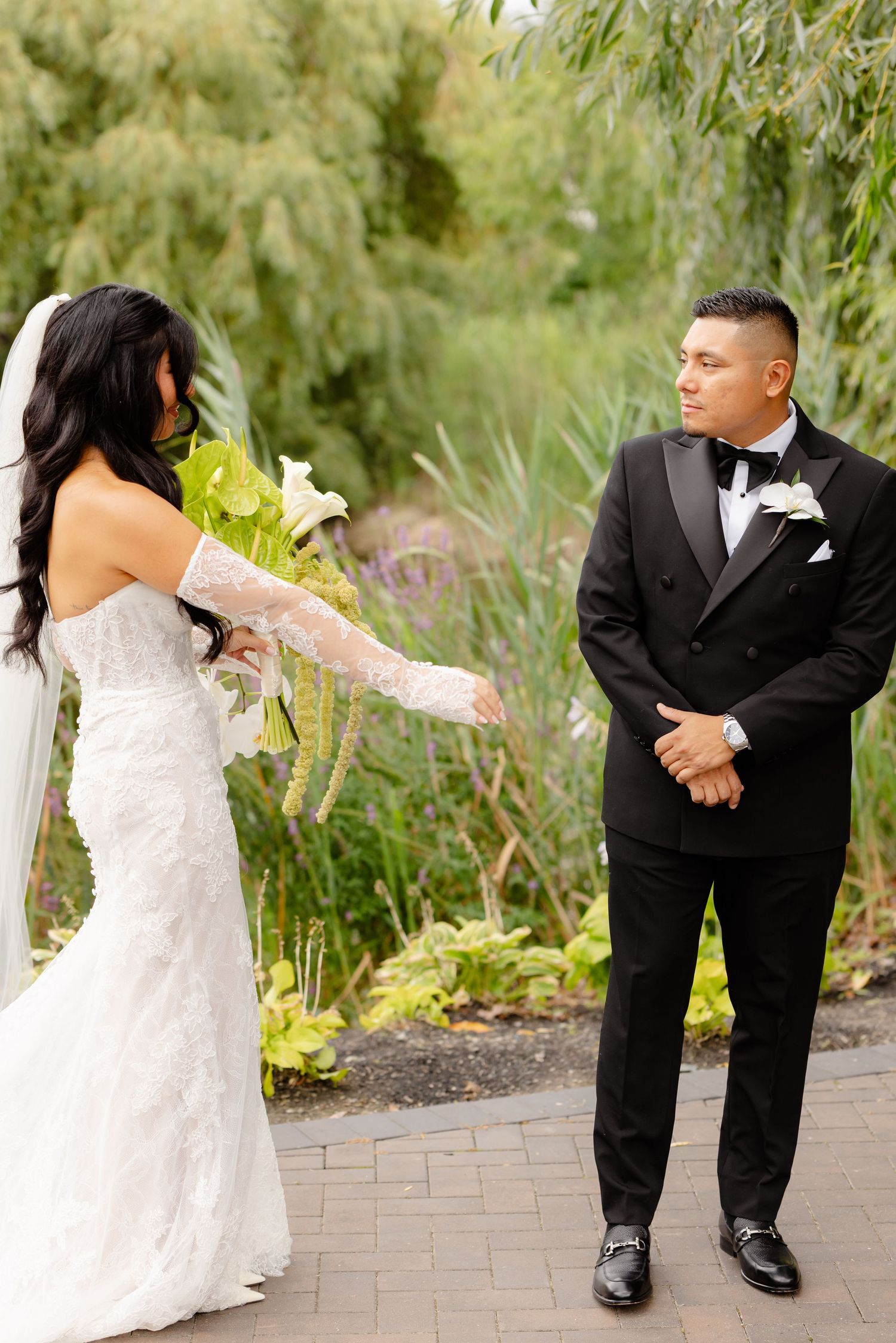 A series of candid wedding photos shows playful moments between a bride in lace and groom in black tuxedo on brick path.