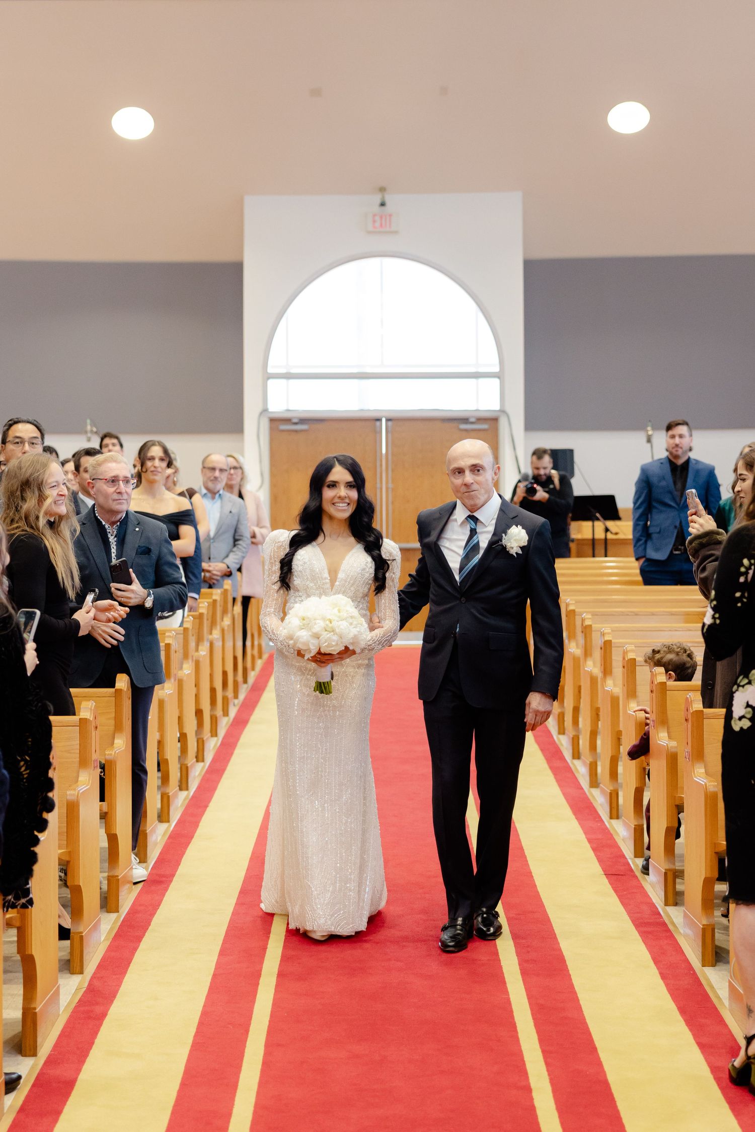 A couple walks down the church aisle after their wedding ceremony while guests celebrate.