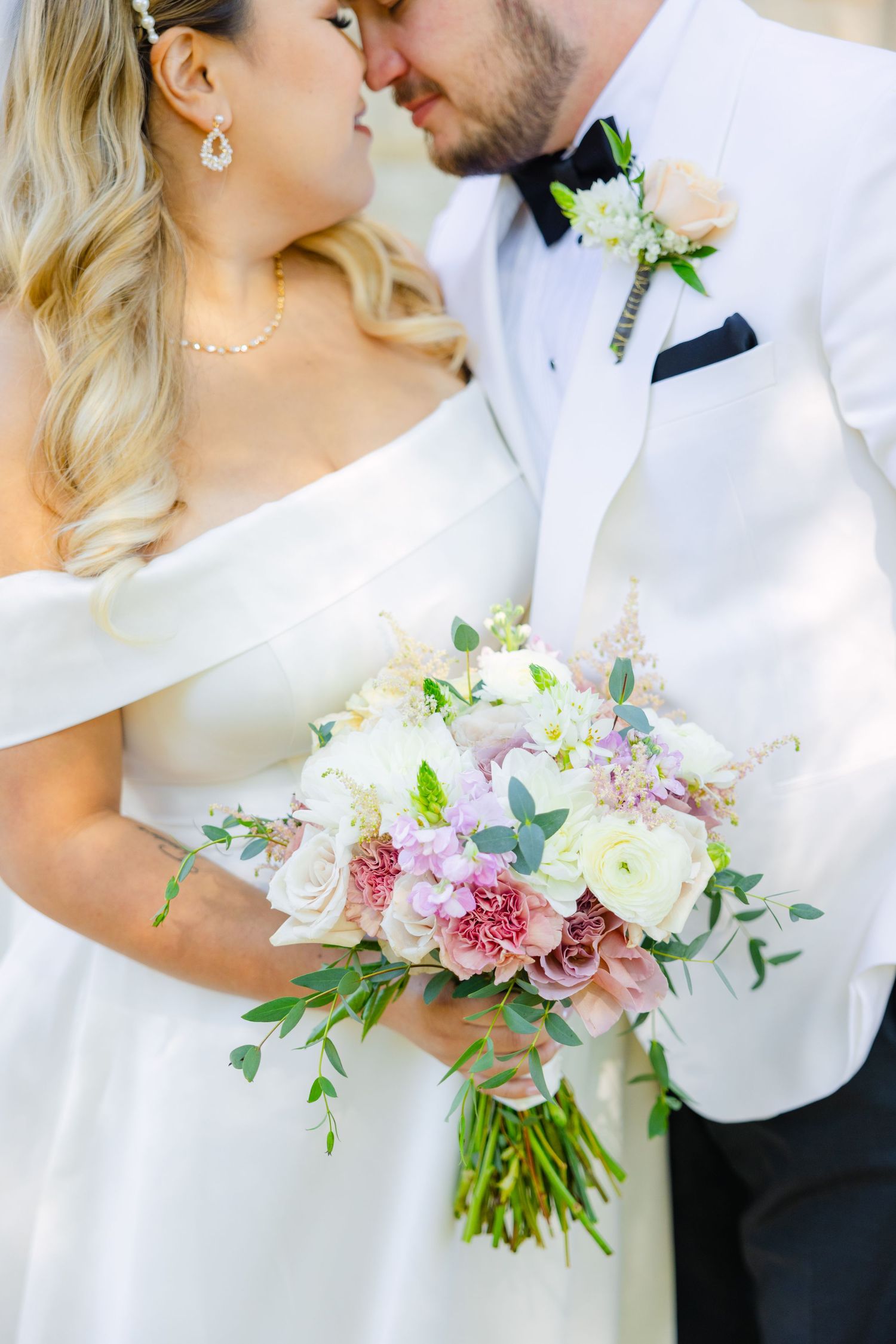 A close-up wedding photo shows delicate details of the bouquet and intimate pose between the couple.
