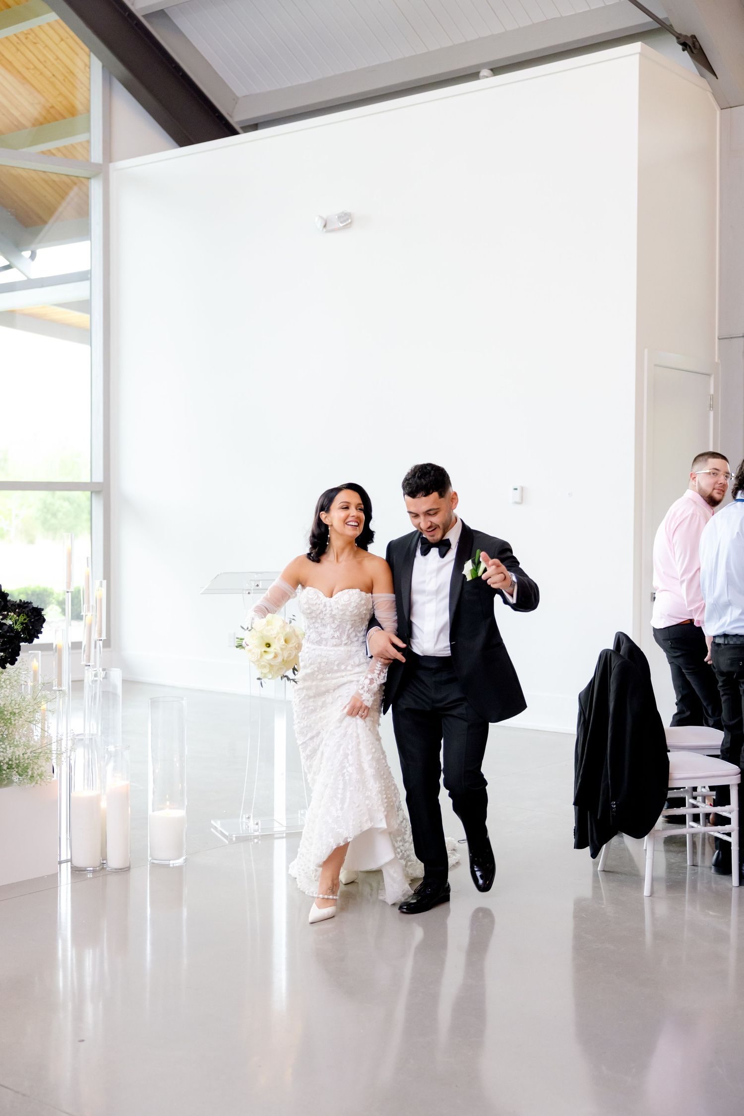 A couple makes their grand entrance at a modern wedding venue with floor-to-ceiling windows.