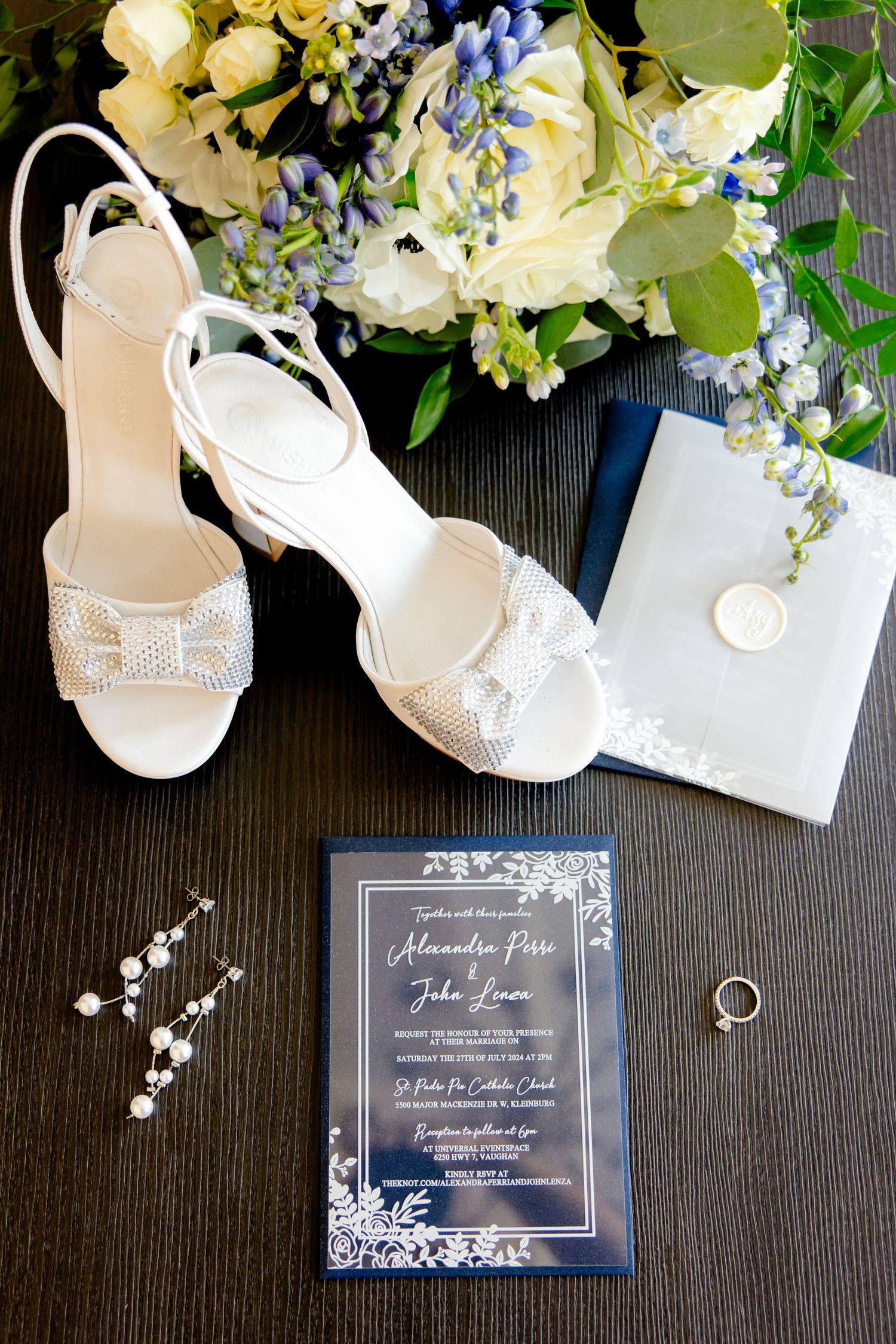 Wedding invitation flat lay with white heeled sandals and floral accents.
