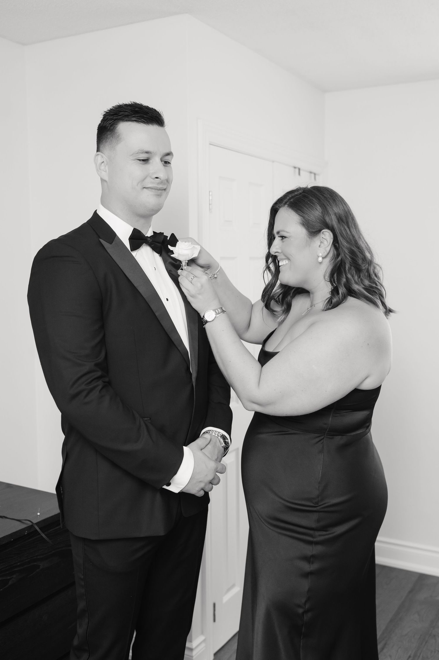 A formal black-tie preparation moment captured in black and white photography.