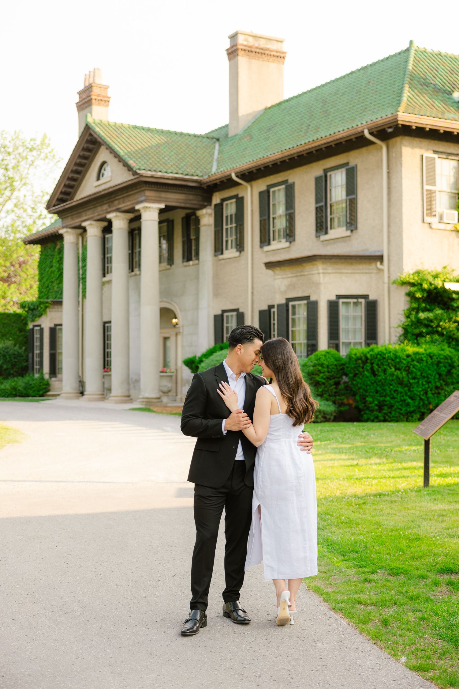 Romantic moment between couple in formal attire outside historic mansion.