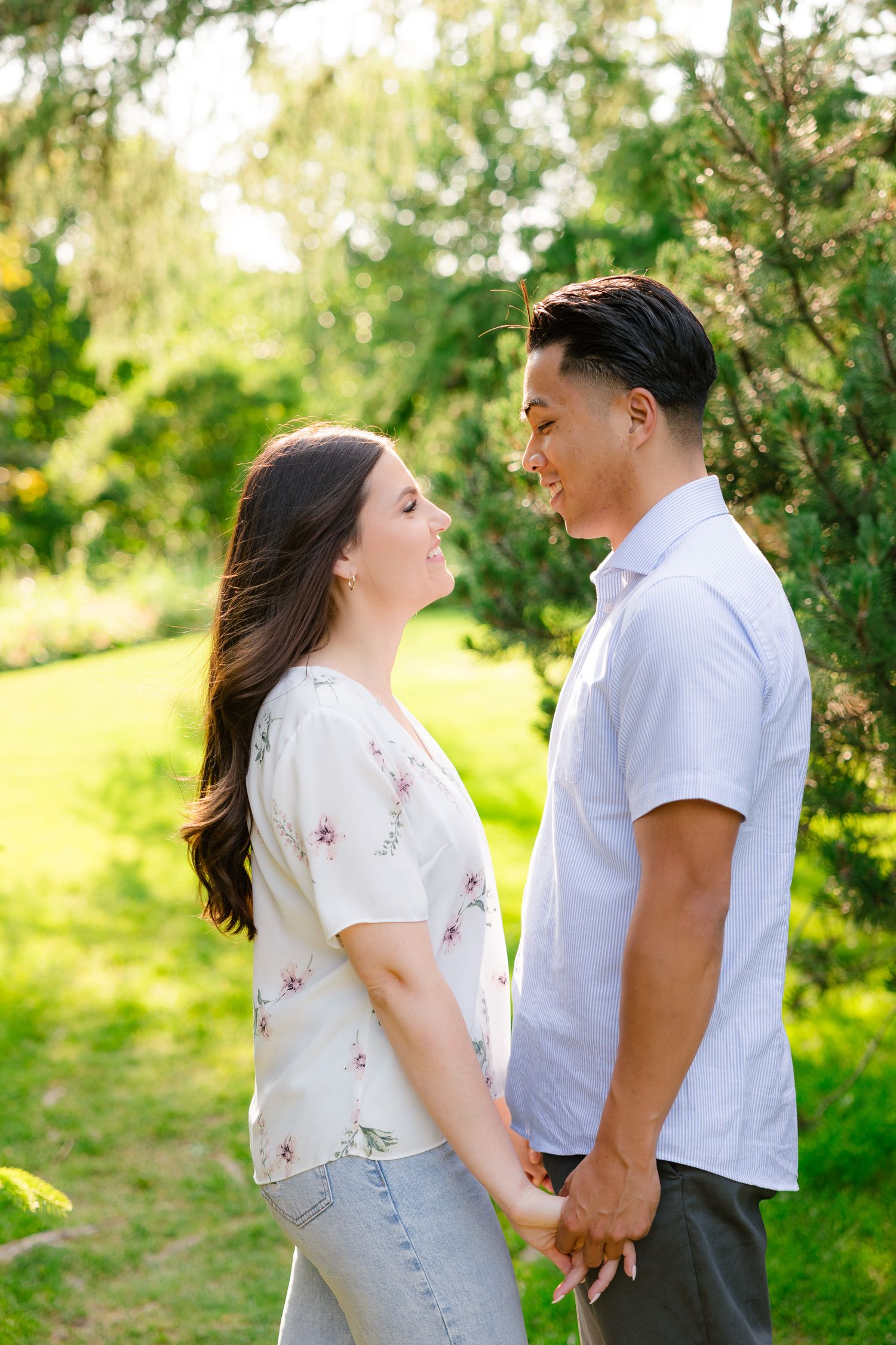 A tender moment between a couple in casual attire standing in a lush garden setting.