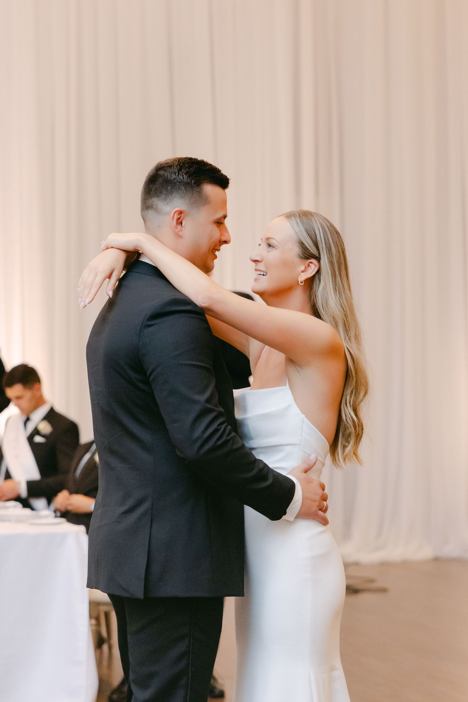 Romantic moment during wedding first dance beneath soft drapery and warm lighting.