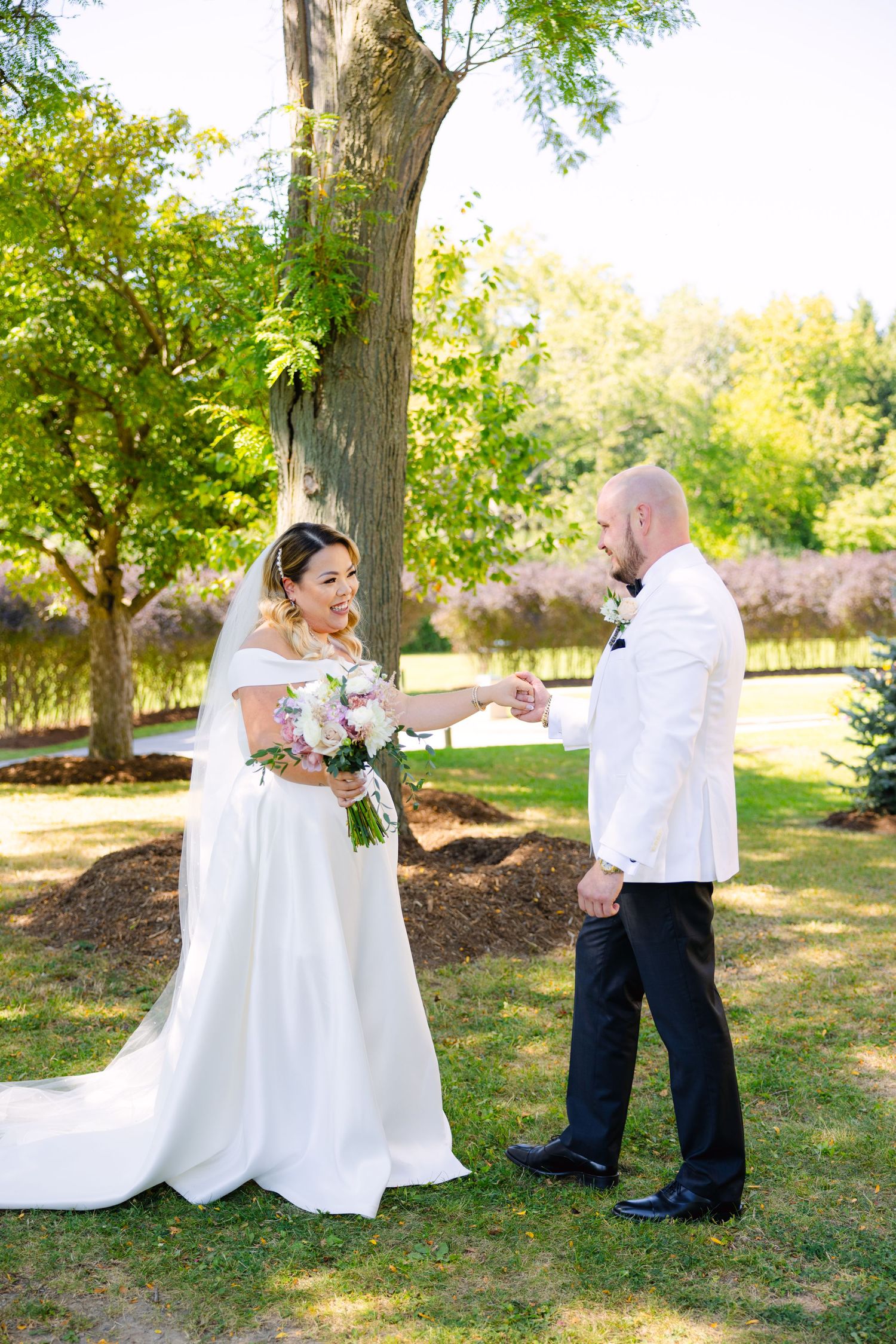 Elegant garden wedding scene with couple exchanging rings under green foliage.