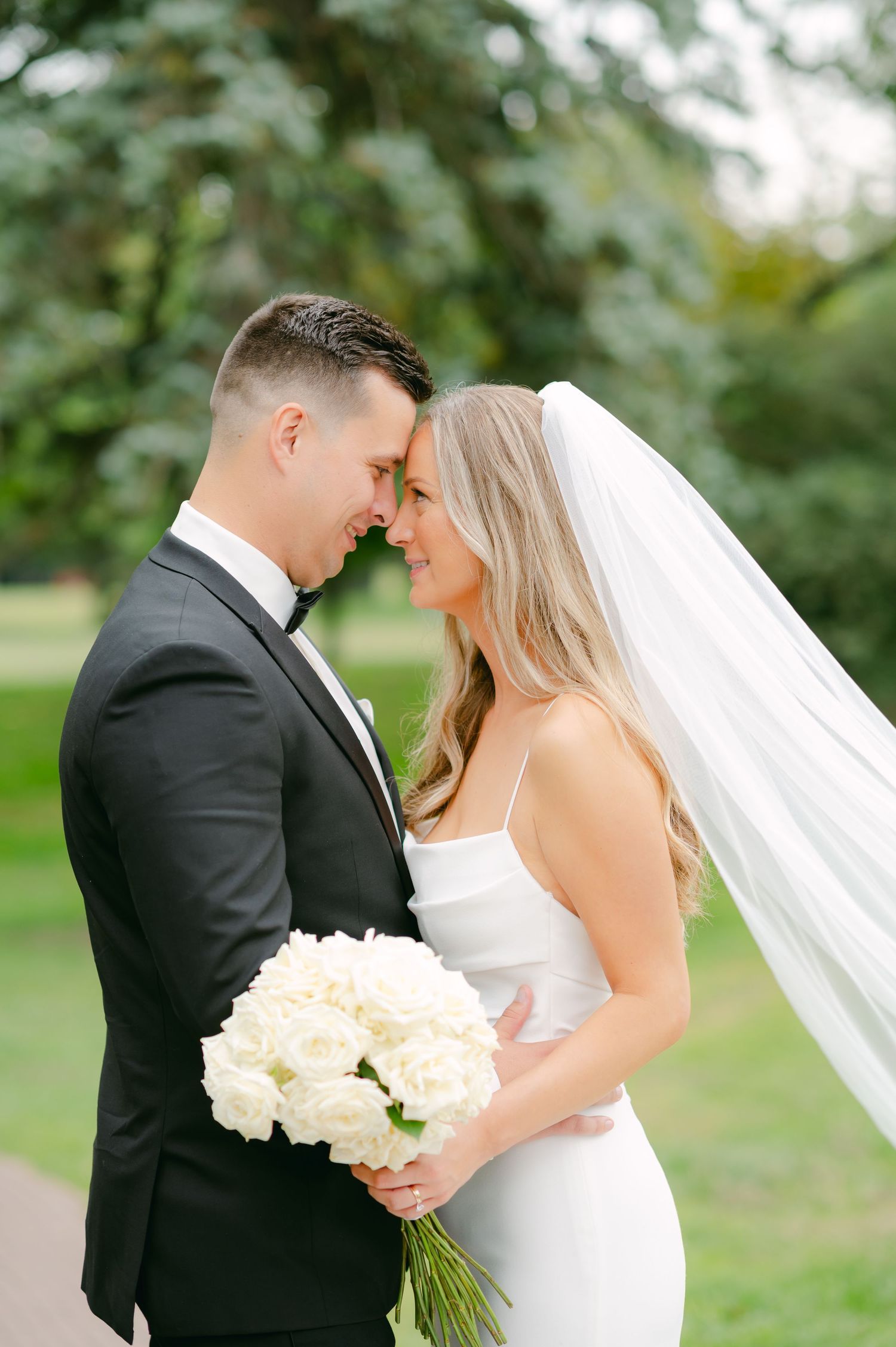 Romantic wedding portrait in garden setting with white rose bouquet.