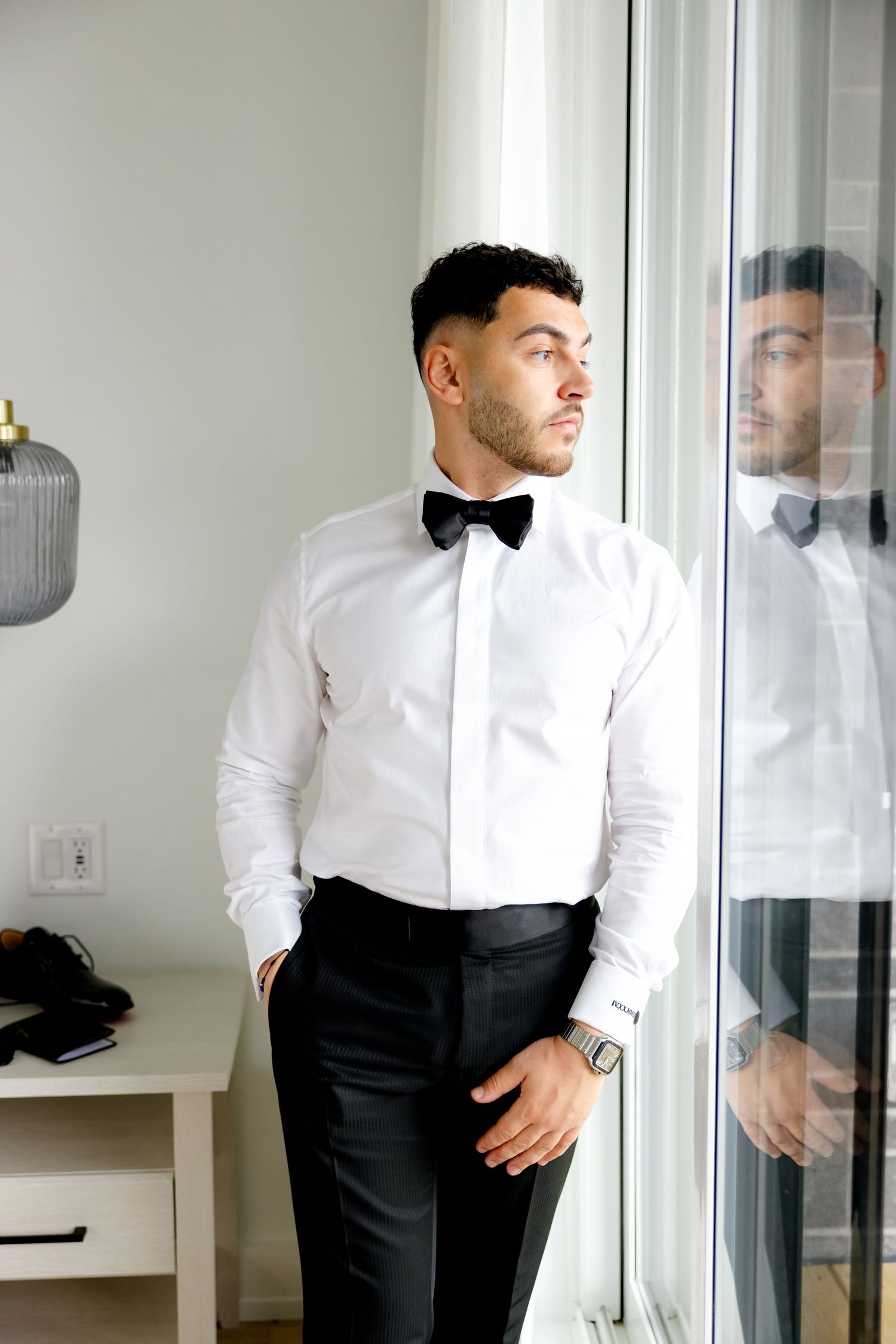 Classic black and white formal wear ensemble with bow tie and dress shirt by window.