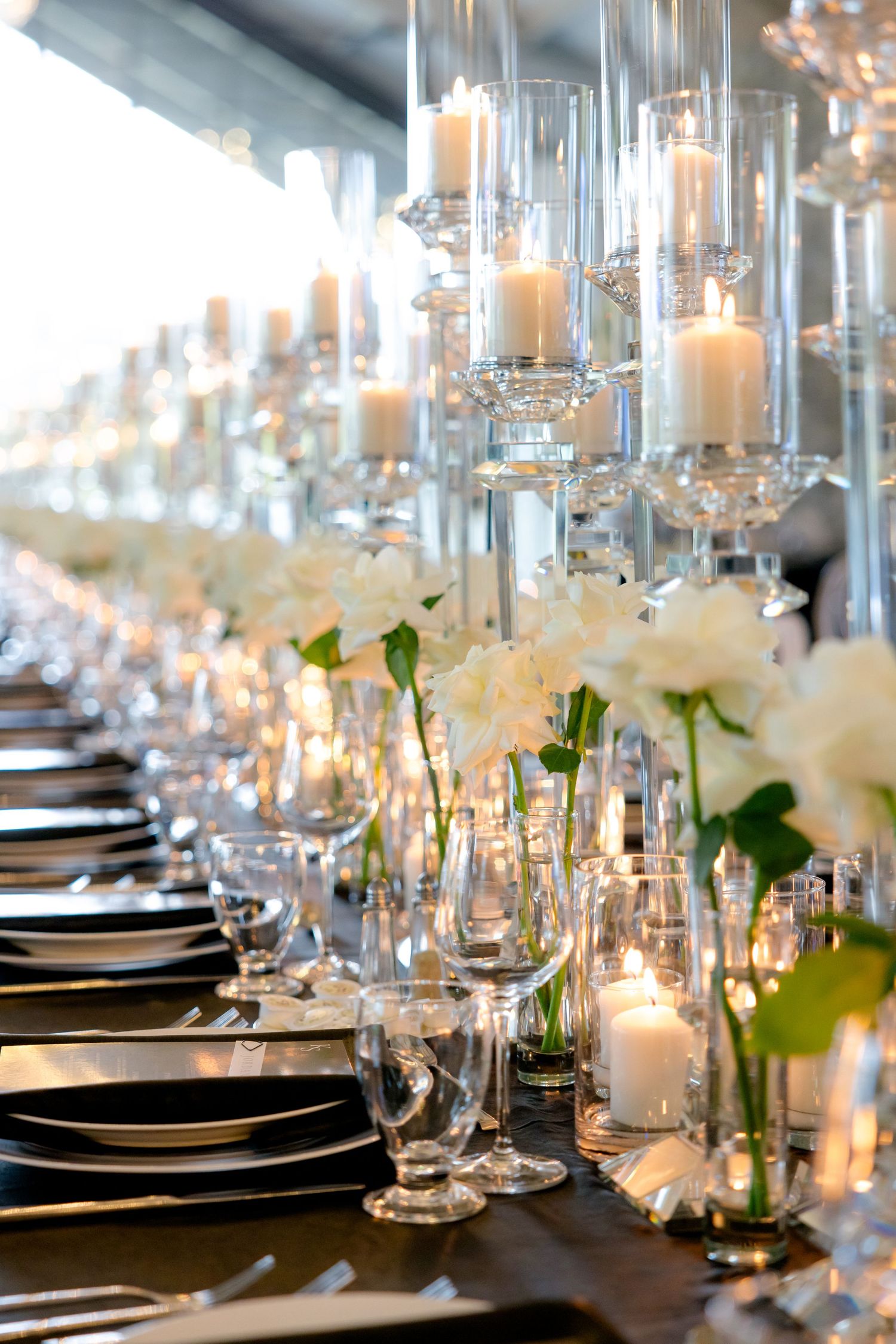 Elegant wedding table setting with suspended glass candleholders and white floral arrangements.