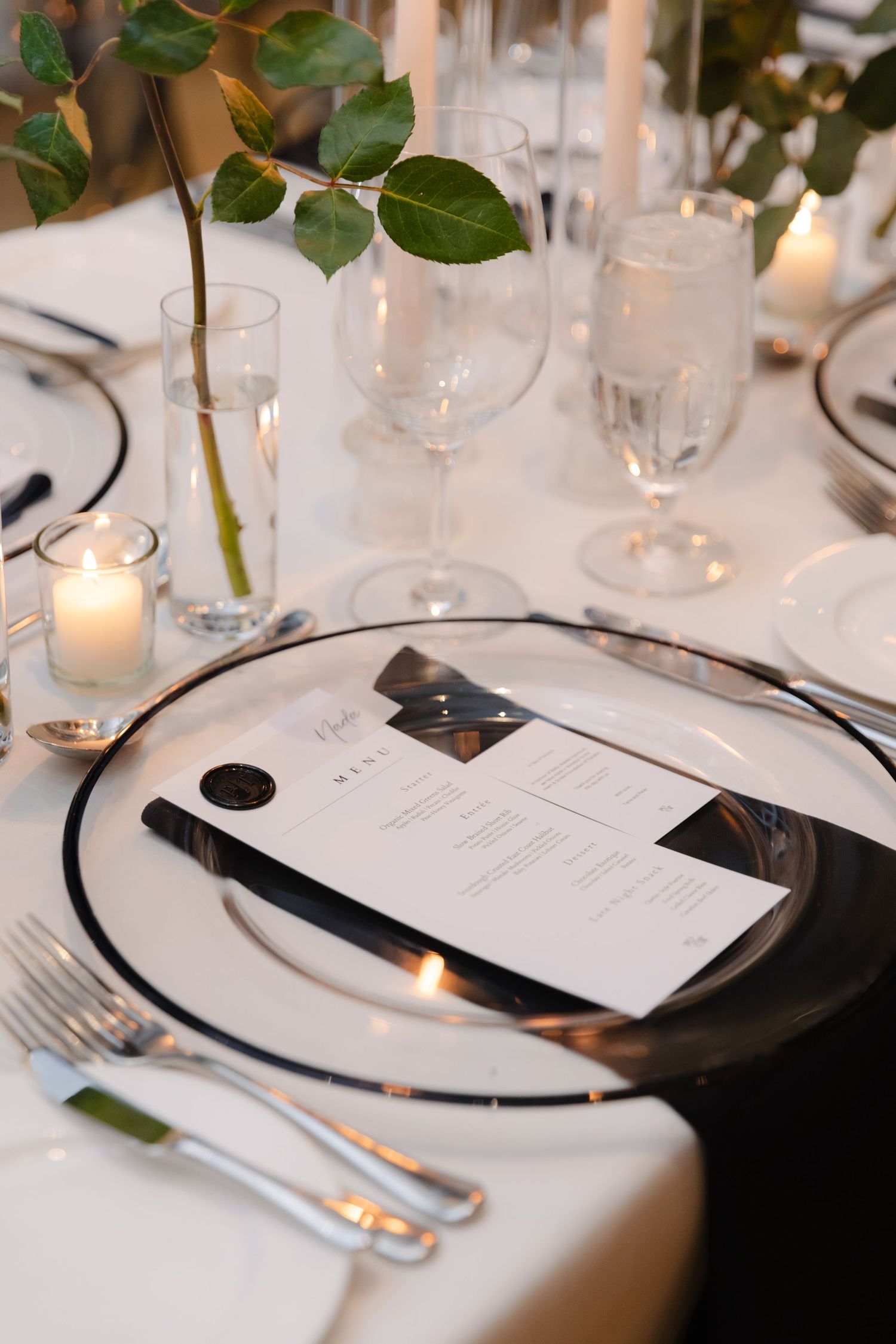 Close-up of formal place setting with menu card, crystal stemware, and single rose.