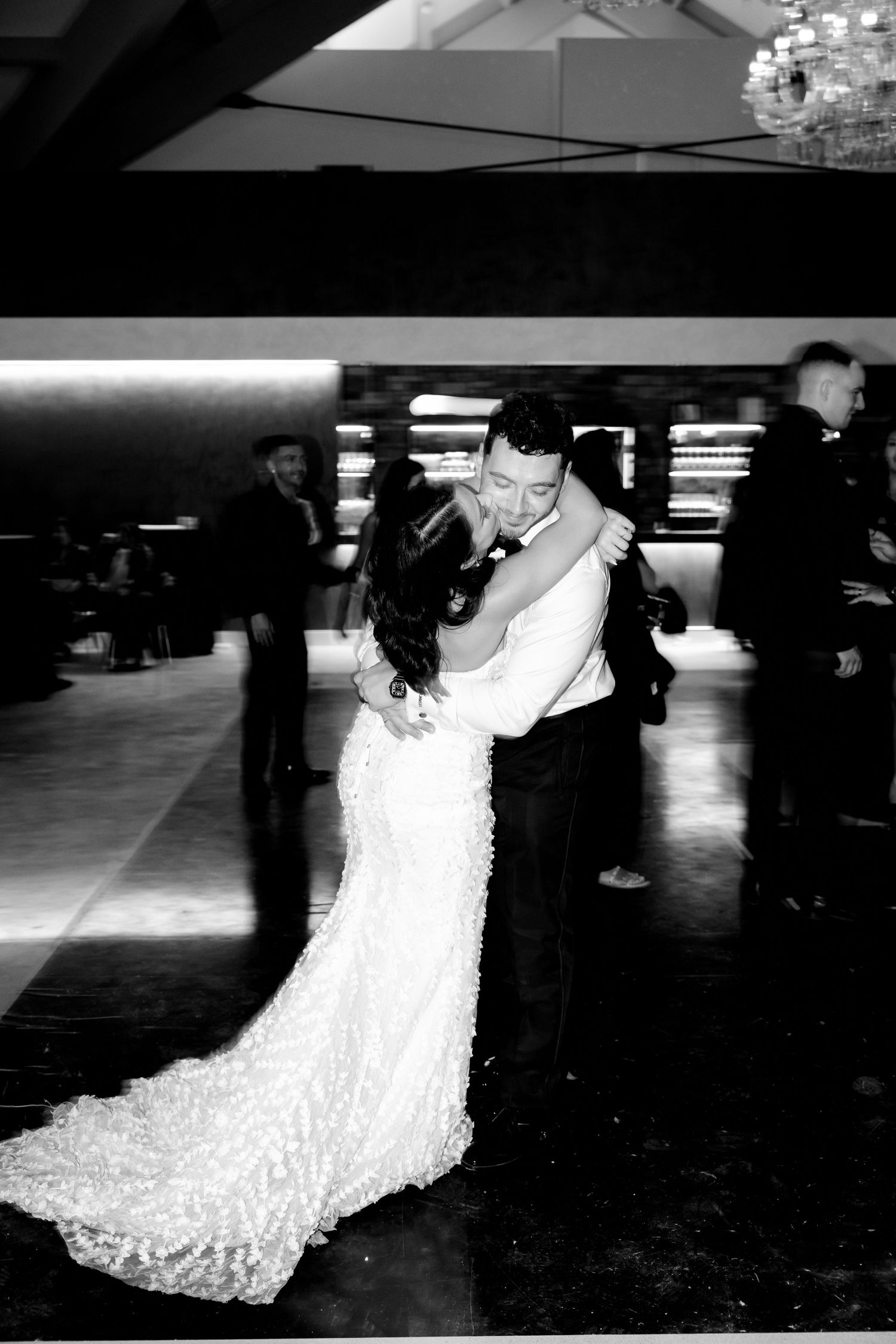 Black and white image capturing a romantic slow dance at an elegant wedding reception.