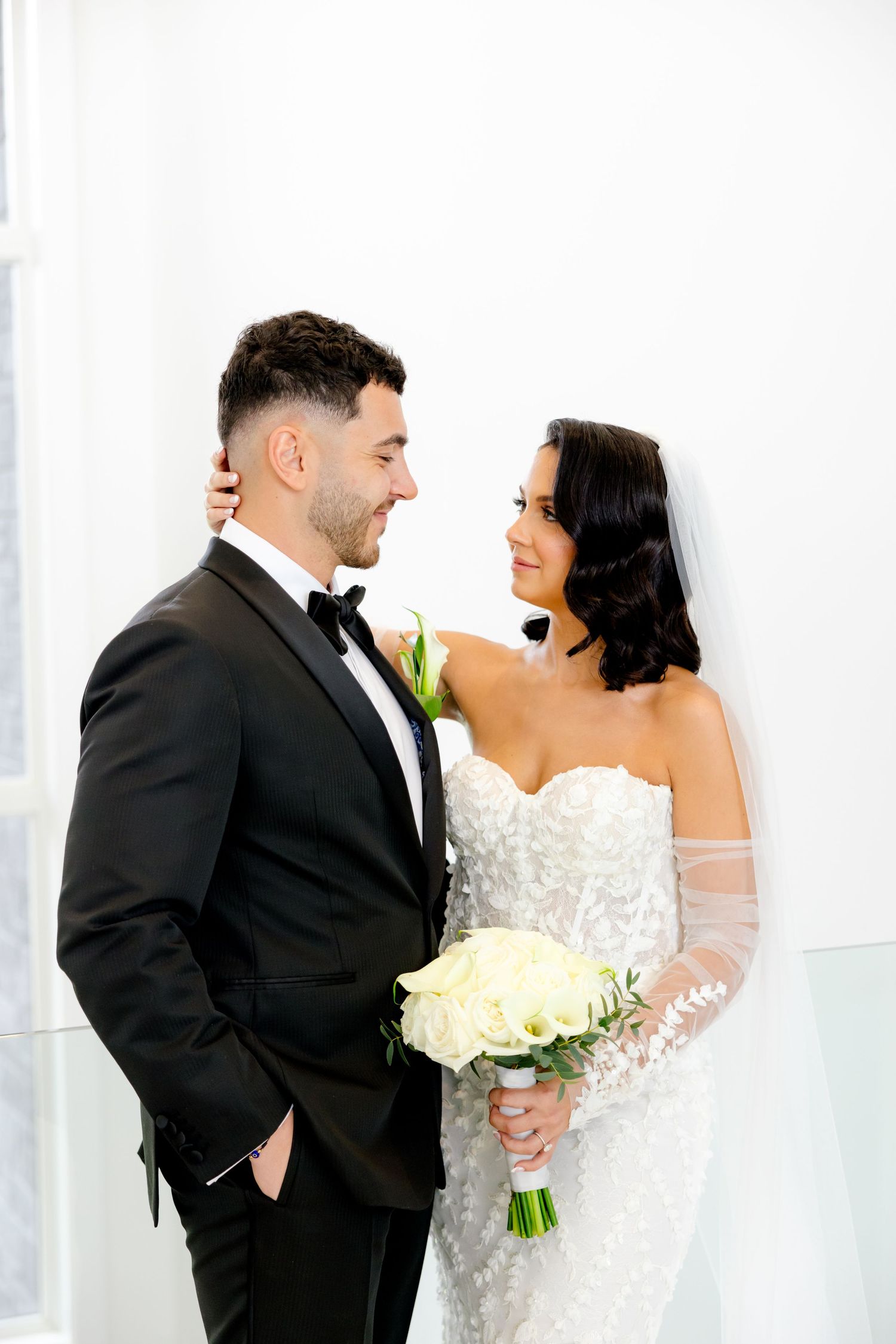 Romantic wedding portrait of couple sharing intimate moment against white background.
